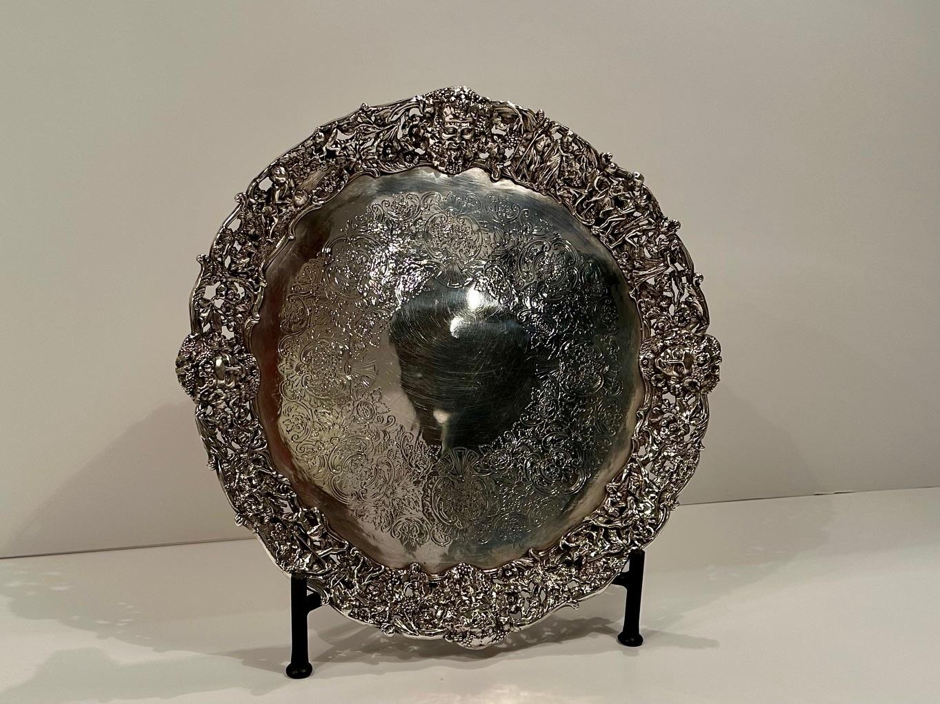 Magnífica bandeja redonda de plata con relieves increíblemente ornamentados en la periferia, con escenas de caza, ciervos, ninfas y elementos figurativos.  También hay hermosos pies de delfín y de concha.  Sin sello distintivo.