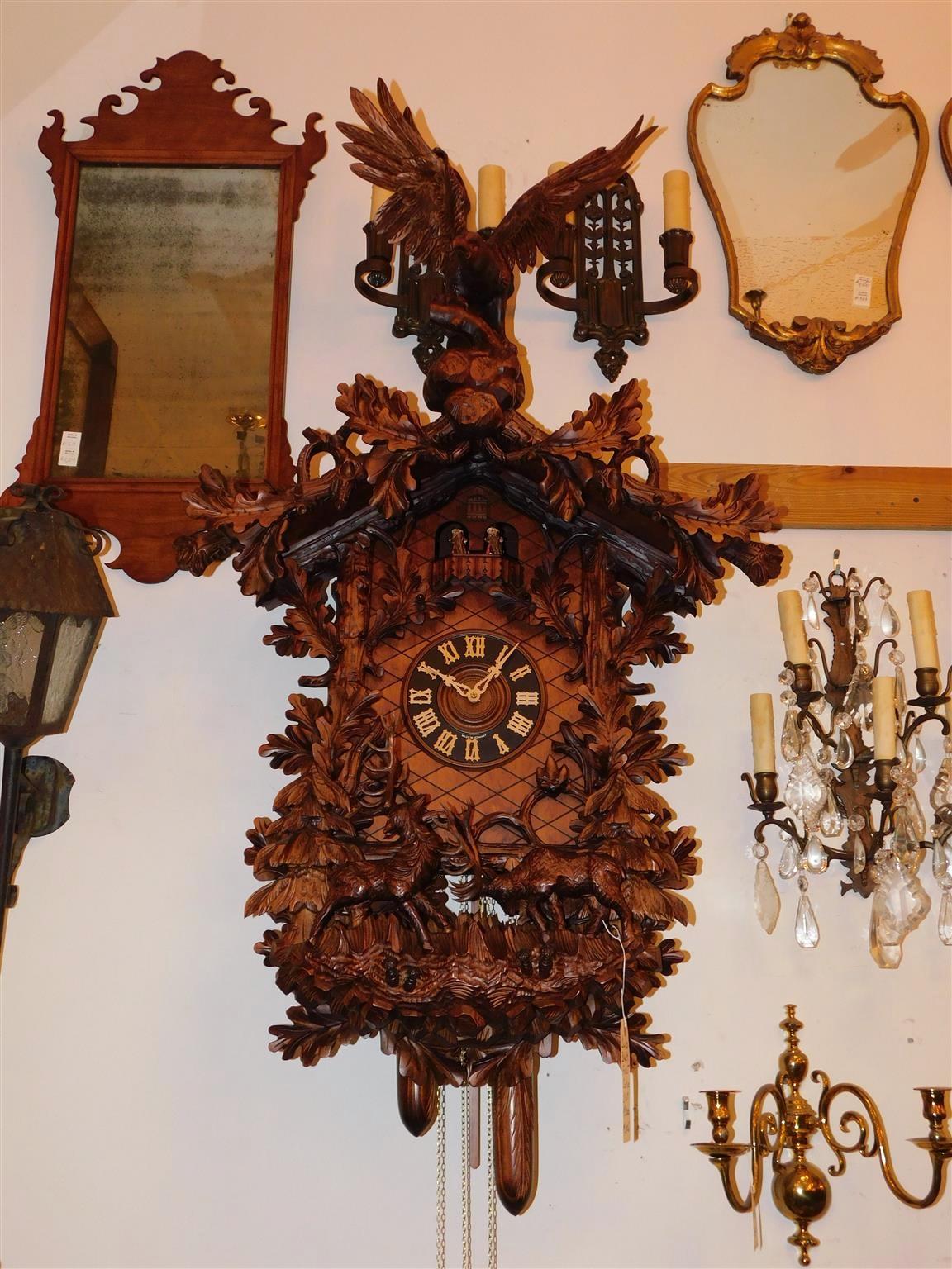 The Linden wood case of grand proportions has a carved realistic perched spread winged eagle with fighting stags within a wooded landscape all amongst a branched garland of oak leaves. The weight-driven movement activating the timekeeping and the