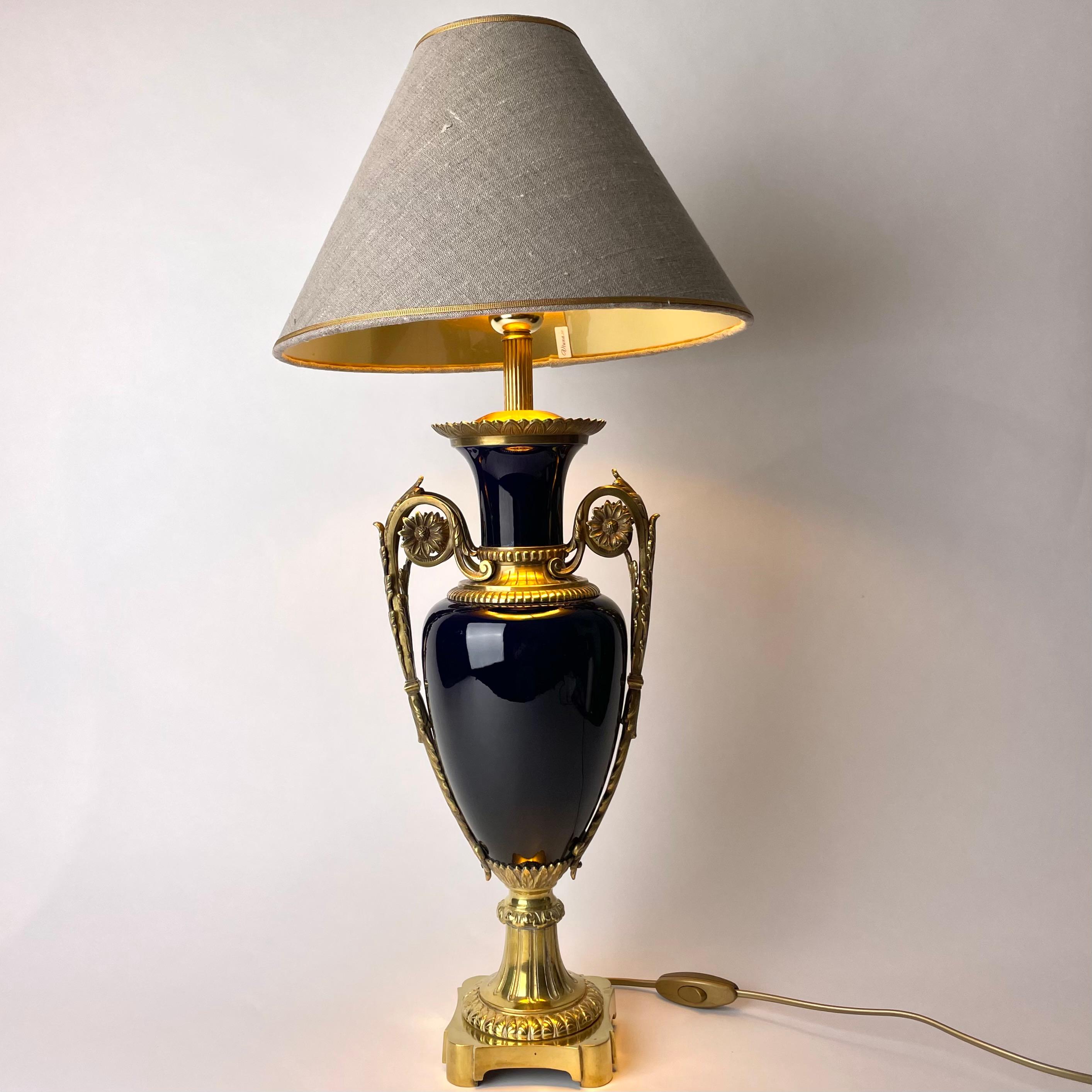 Magnificent Table Lamp in bronze & porcelain. Louis XVI style from the early 20th Century.  Elegantly decorated and with a sophisticated color on the china. 

Newly rewired electricity 

Lampshade in linen with gilding on the inside to give a cozy