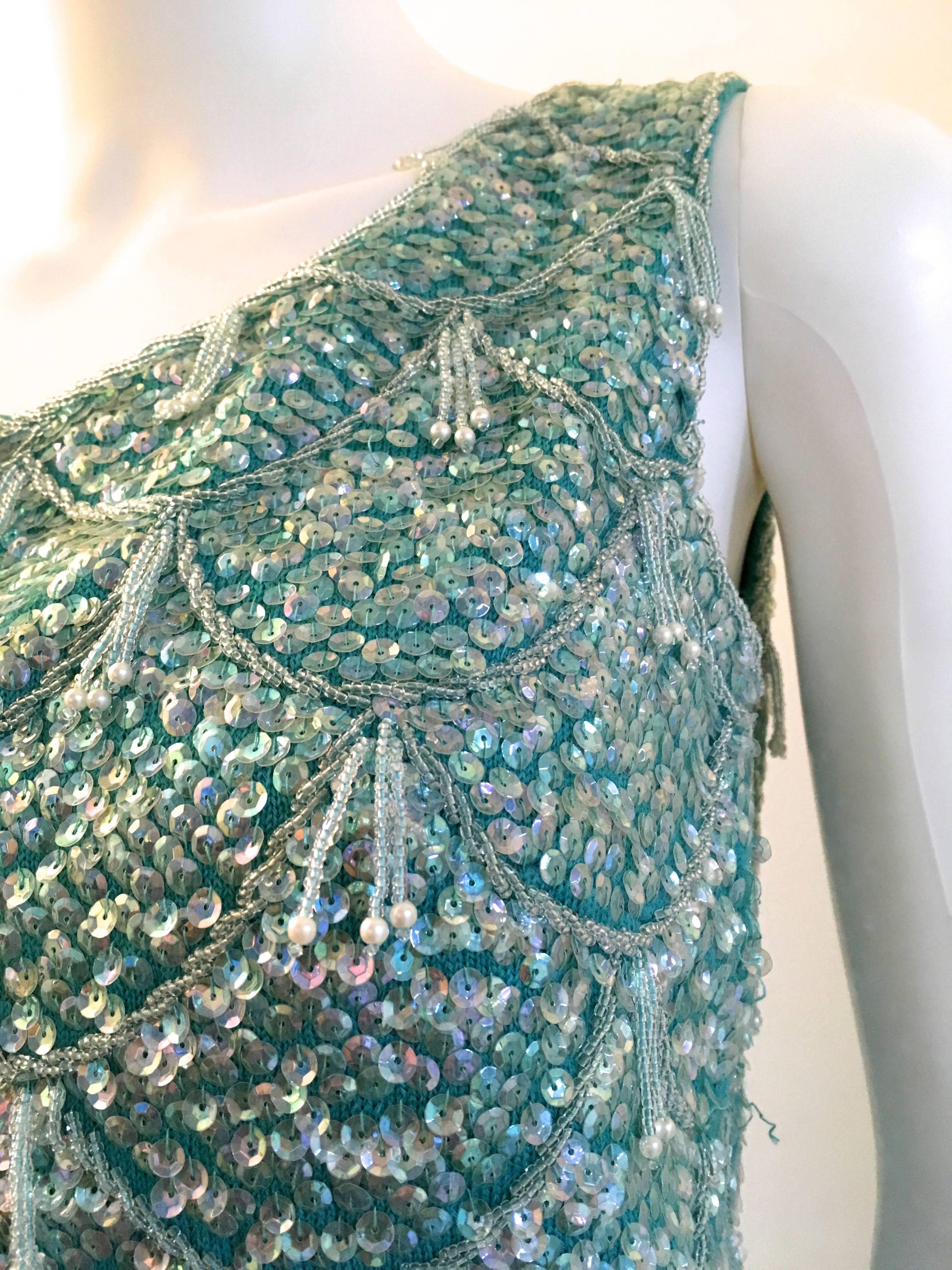 Presented here is a gorgeous sleeveless top from the 1970's. This beautiful top is a composition of sequins and rhinestones faceted across the entire garment. The top zips down the back and is composed of colors of aquamarine, blue, silver and