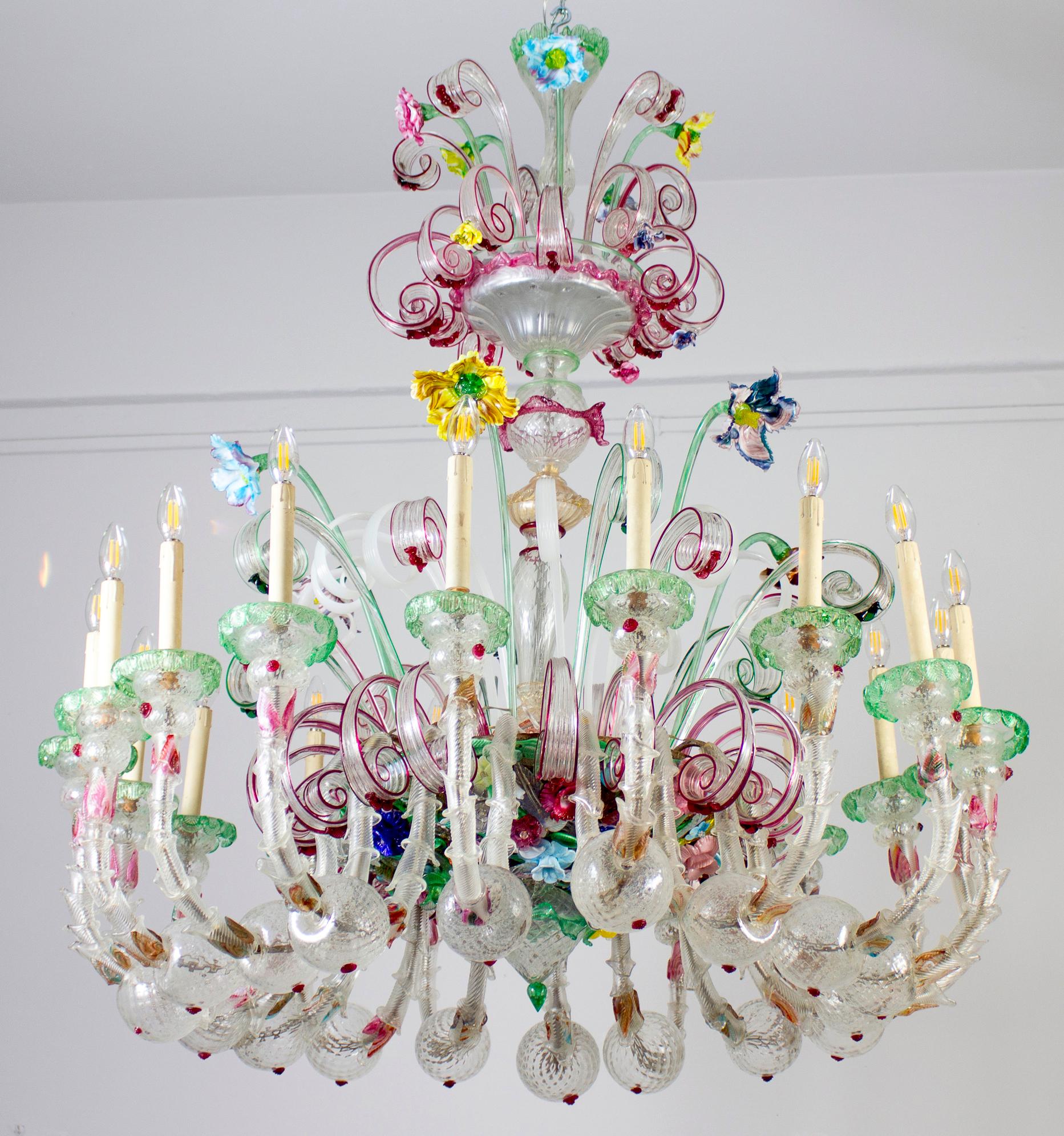Spectacular Ca' Rezzonico Multicolor Murano glass chandelier with 18 arms. The glasses are embellished with green and amethyst  inclusions in perfect condition. Brightly colored glass paste flowers. It is a true work of art. 

 18 E 14 light bulbs