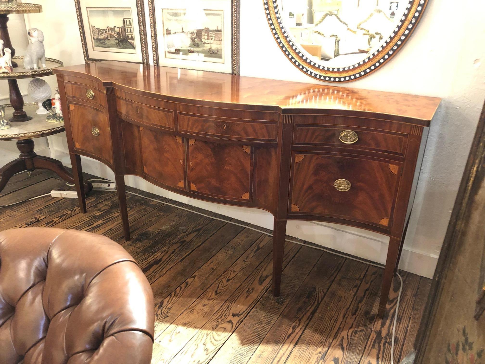 A beautifully crafted mahogany sideboard having stunning mahogany veneers and decorative inlay, carefully crafted fluted legs, solid brass hardware, English dovetail joinery, and solid wood construction. There are 4 drawers along the top, 4 lovely