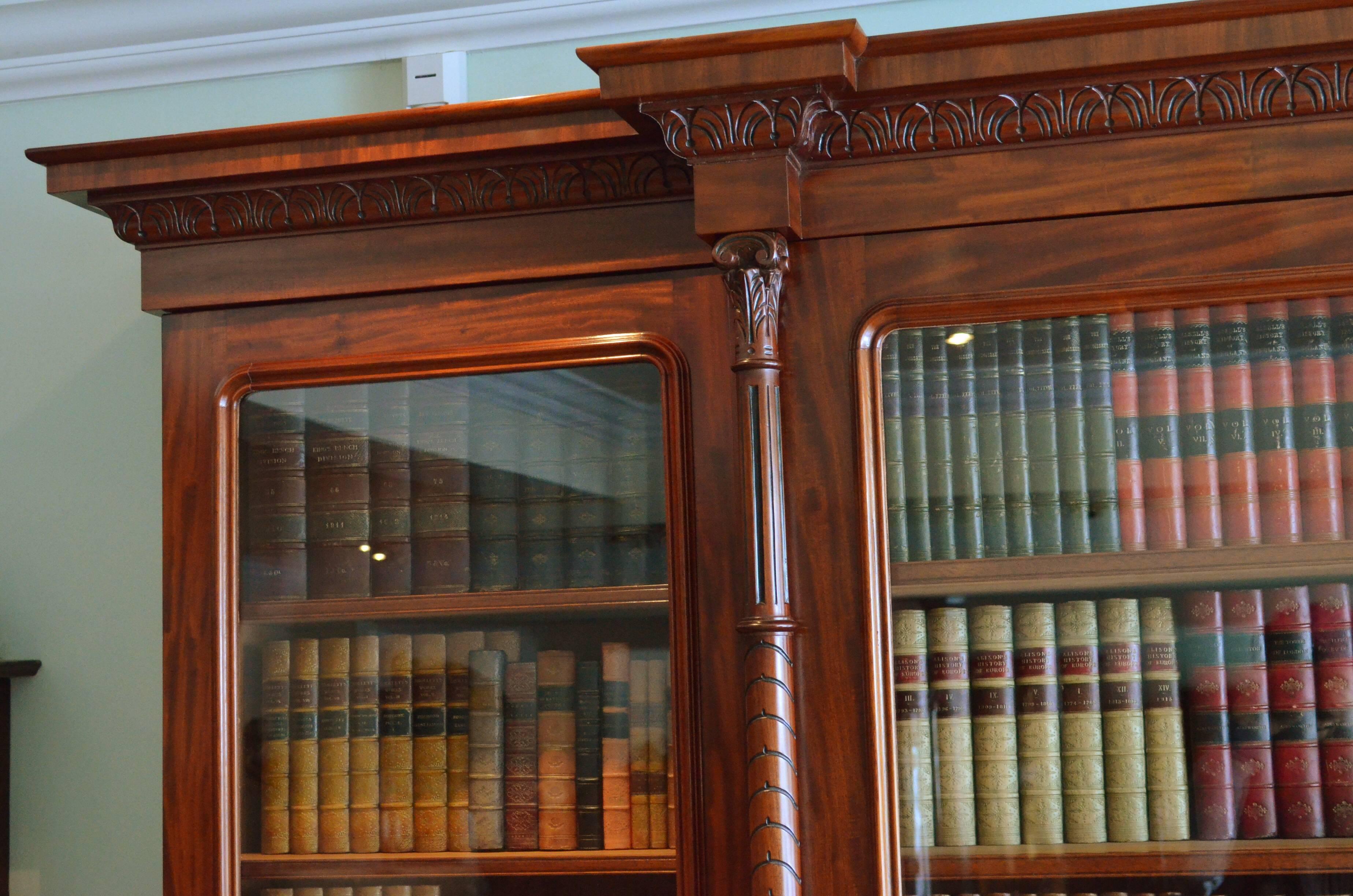 Sn4274, fine quality Victorian, breakfronted bookcase in figured mahogany, having moulded cornice with finely carved edge above a projecting centre door enclosing four height adjustable shelves and fitted with carved and fluted columns, all flanked