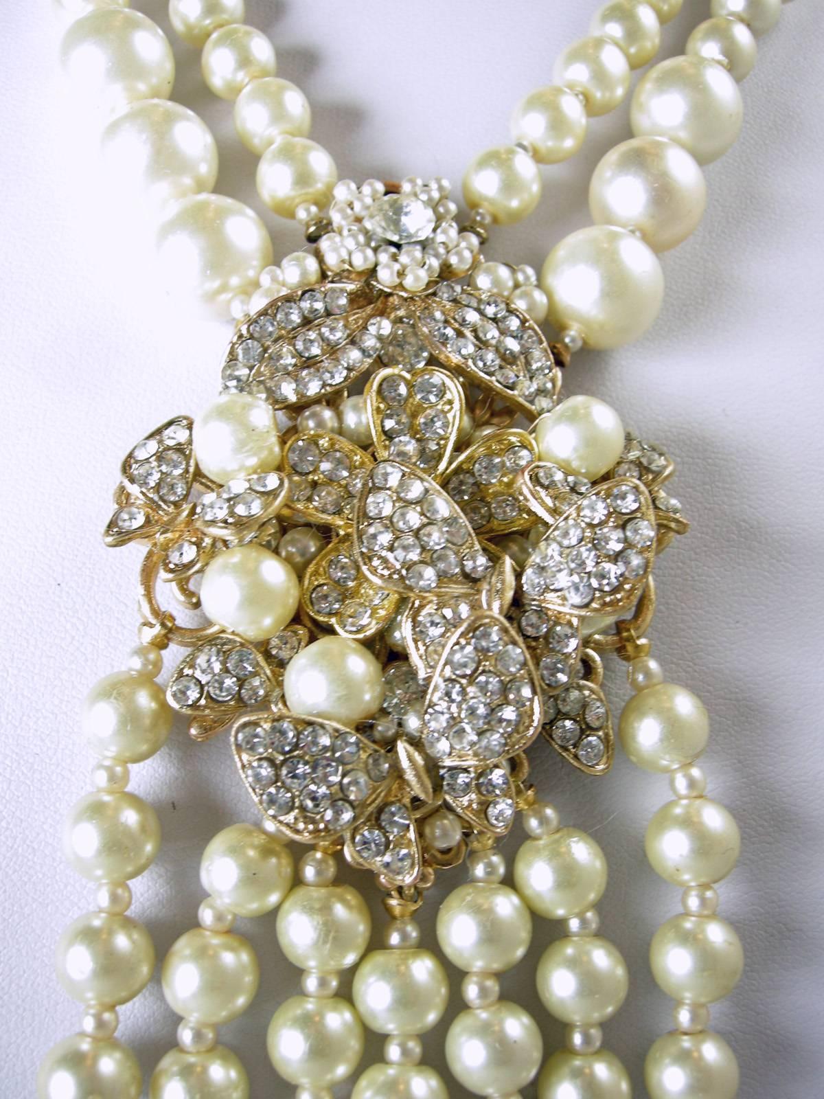 This necklace is in the style of Haskell and that is all we know about it.  It features a magnificent centerpiece with 7 drop strands composed of faux pearls in a gold tone setting.  This necklace measures 17-1/2” long with a slide in clasp. The