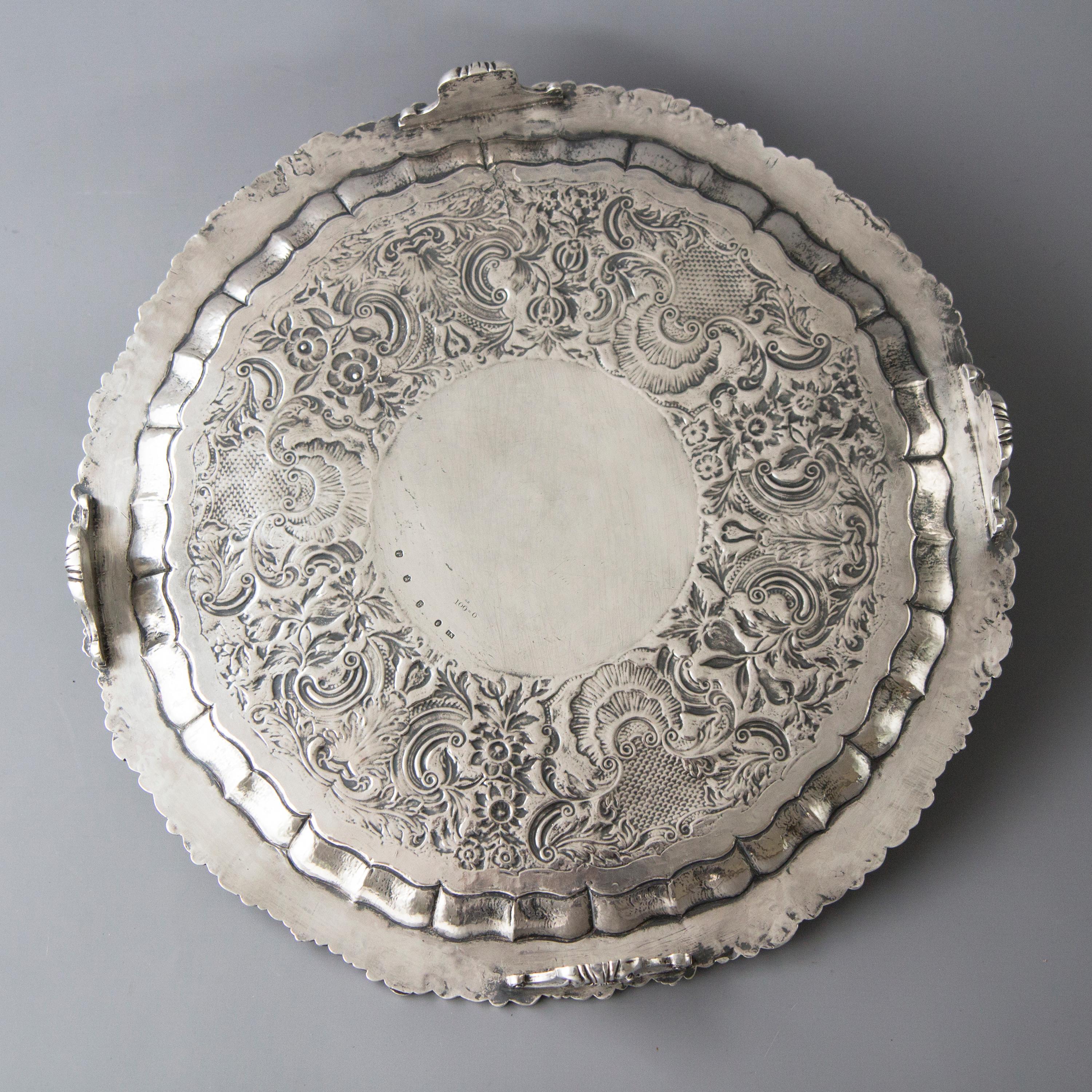 A very large circular salver with cast and applied rim of floral and foliate design. The central plate embossed with floral, foliate and shell form arabesques. In the centre is a dedication inscription to Canon Fleming from a member of his