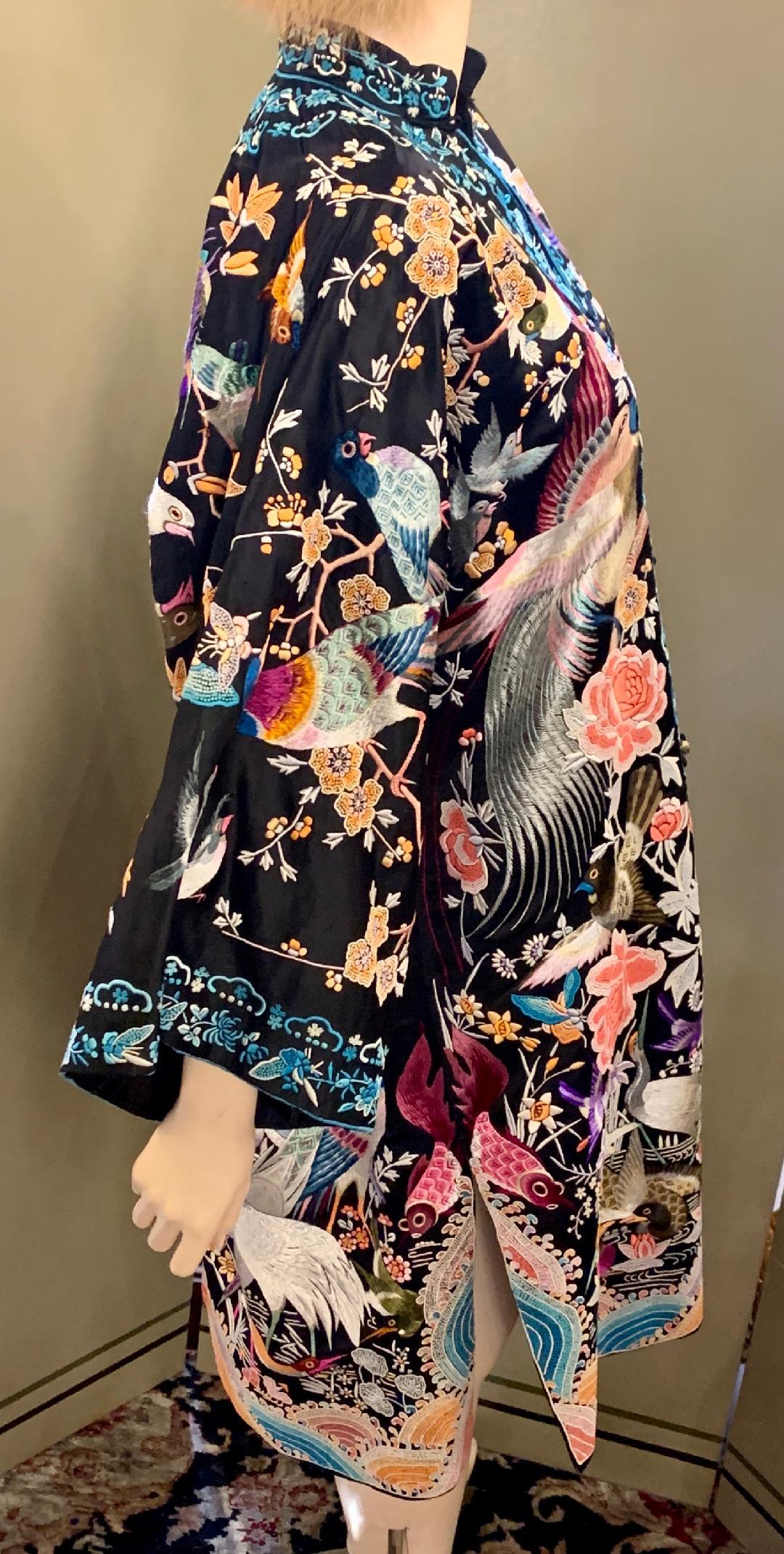 Incredible vibrant handmade black silk Chinese Peacock evening coat or dress is a work of art, lavishly hand embroidered with a highly stylized array of astonishingly beautiful and boldly vivid birds, butterflies, flowers and rainbows. The back of