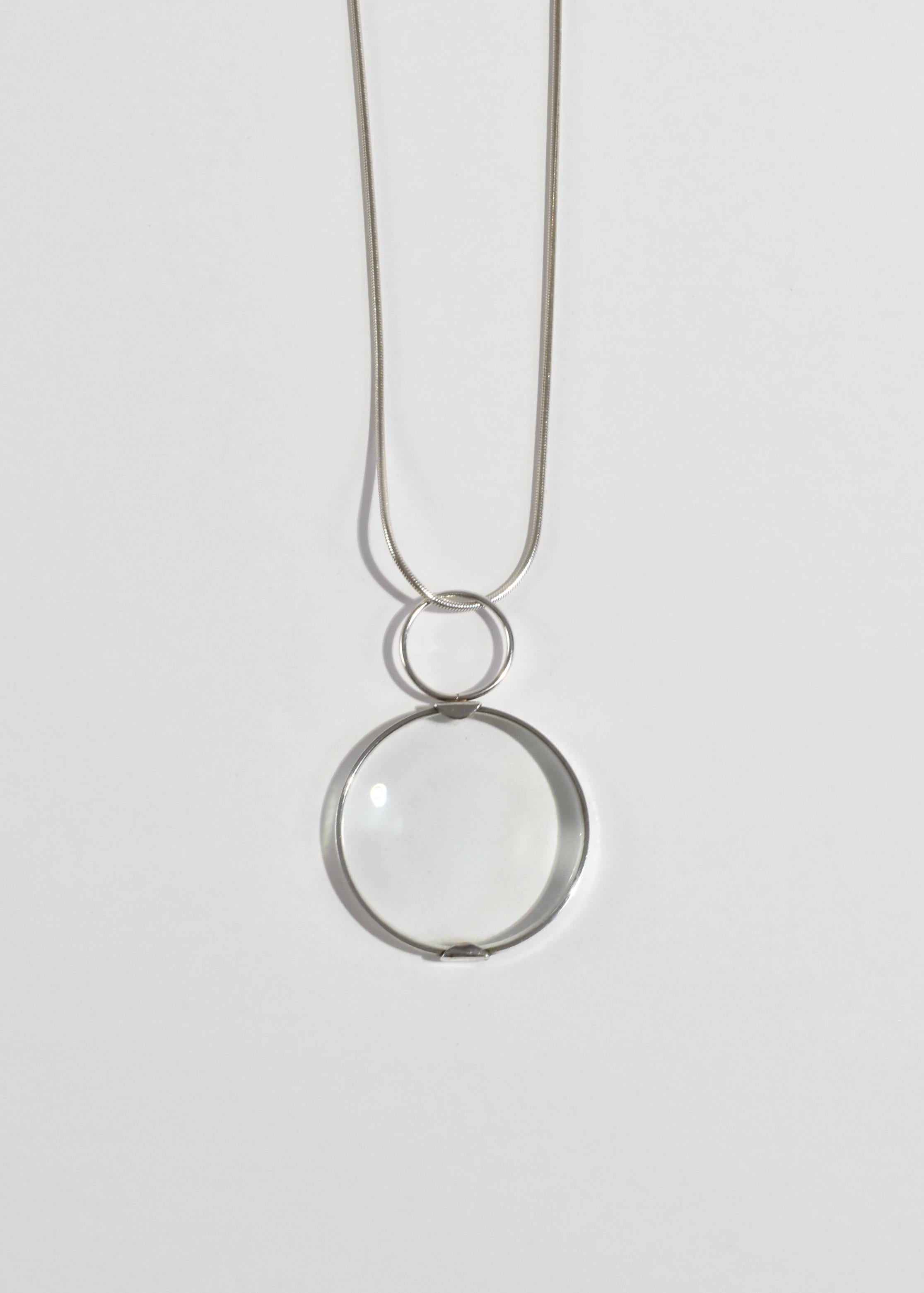 Rare vintage silver necklace with a circular magnifying glass pendant. Stamped Leonore Doskow, sterling, 1973.

Material: Sterling silver, glass.

We recommend storing in a dry place and periodic polishing with a cloth.