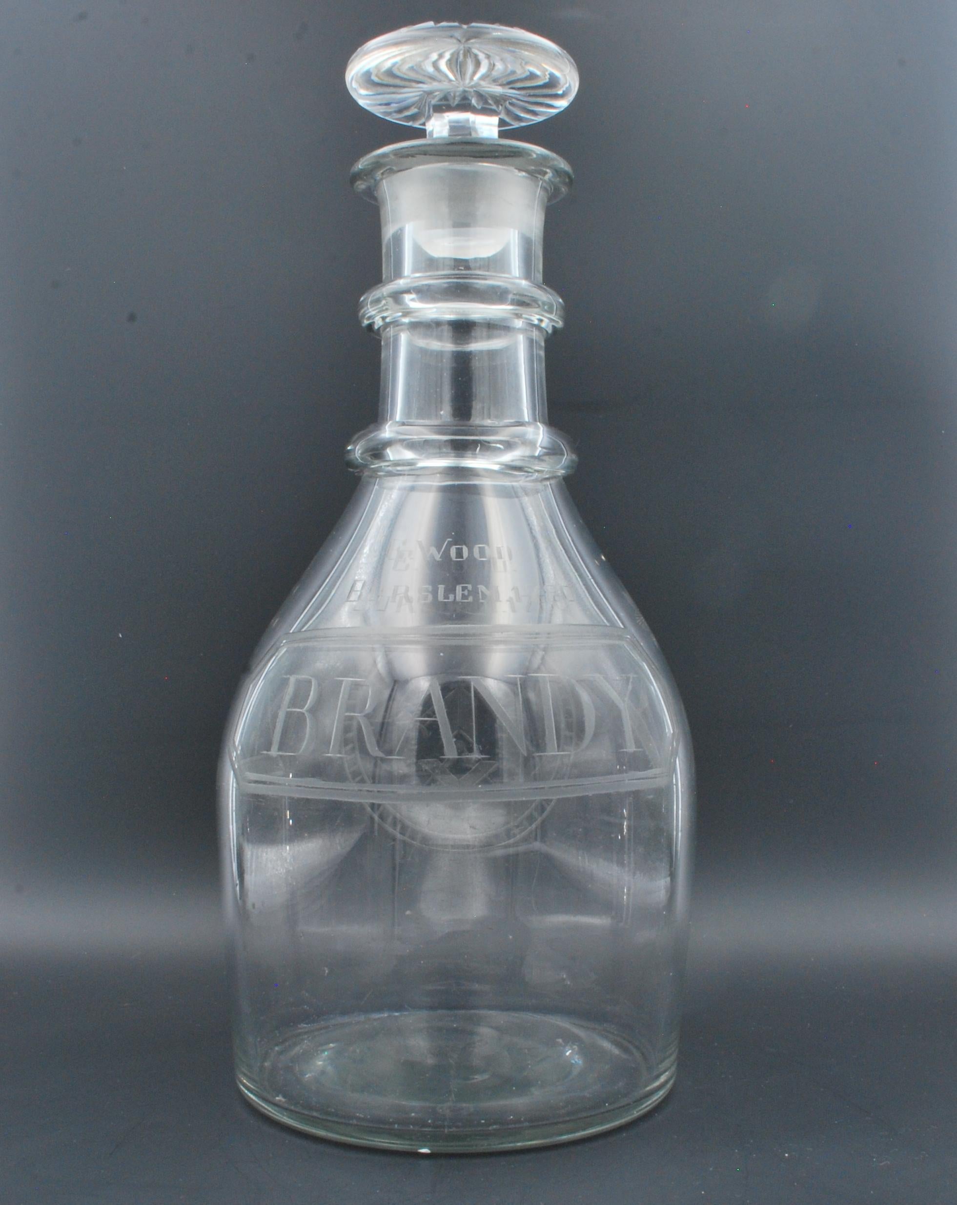 A magnum decanter, made plain in Georgian times. Later etched for brandy, and decorated with Masonic symbols, in imitation of early wheel-cut engraving.

The engraving includes the name of E Woods, Burslem, one of the famous potters of that