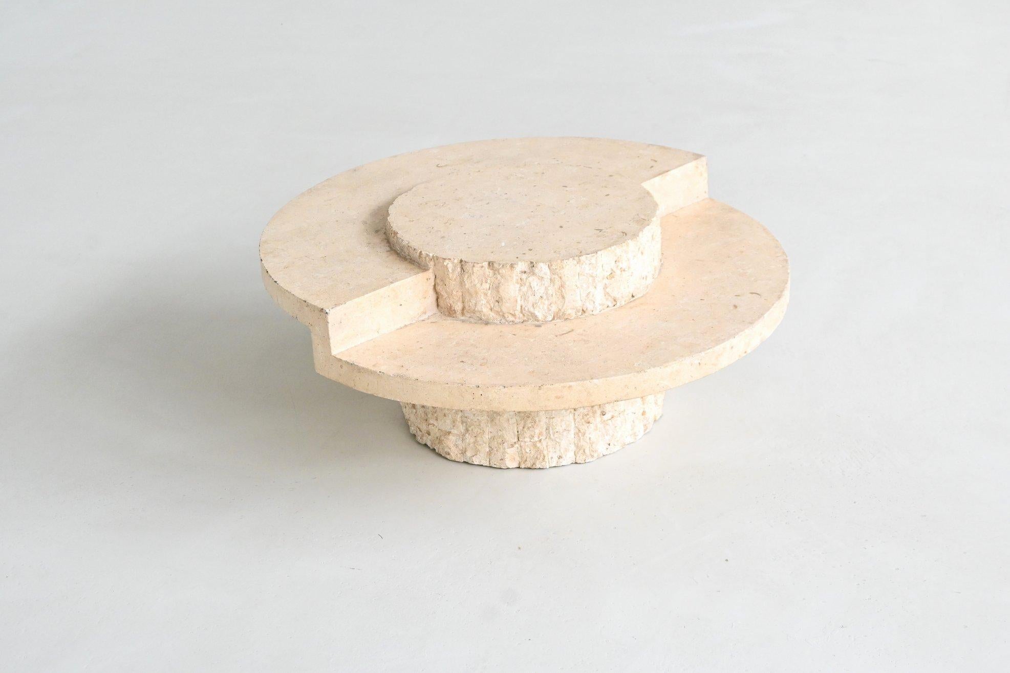 Magnifique table basse ronde sculpturale conçue et fabriquée par Magnussen Ponte, Belgique 1970. Le plateau est en pierre de Mactan blanc crème hautement polie, soutenu par une base de carreaux de pierre sculptée texturée caractéristique. Cette