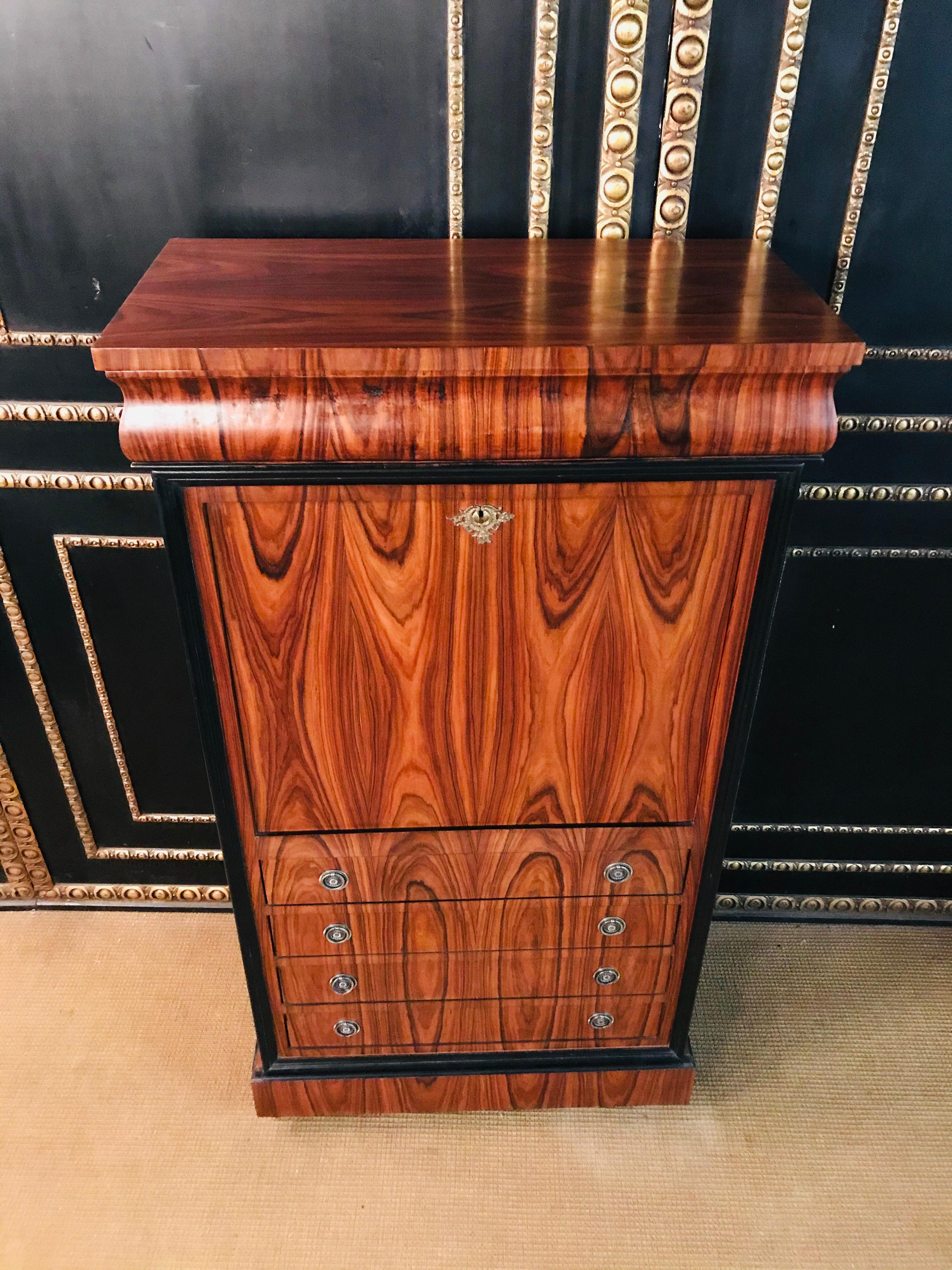 Exotic mahogany, partly blackened, on solid softwood. Rectangular body on flat printed ball feet. Five drawers of different sizes in the front. Straight writing surface, behind it an architecturally structured office division consisting of a wide