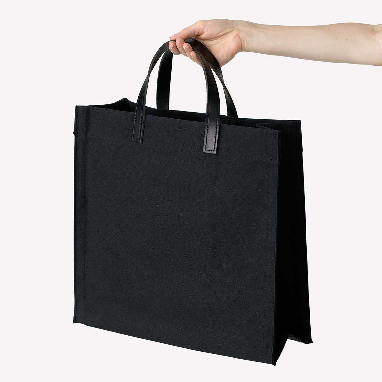 Maharam Bag
Amsterdam 
001 Black/Black

Waxed cotton canvas with leather handles. One interior pocket. Light and dark variation is inherent to this waterproof textile.

Clean with damp cloth.

15 1/2