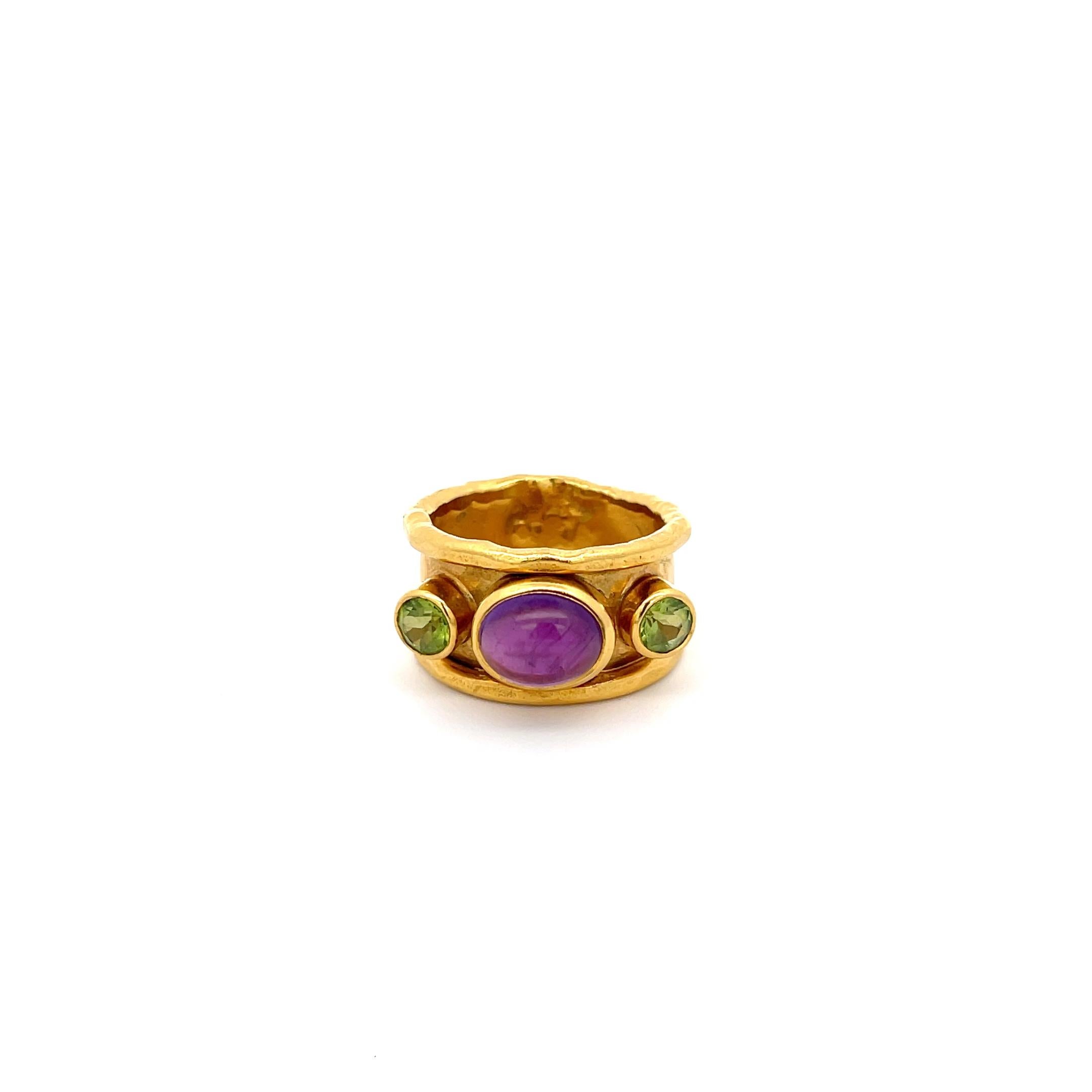Mahie Amethyst and Peridot Wide Band in 22K Yellow Gold. The band features a cabochon cut amethyst accented by two round cut peridots on each side. The band is 13.5mm wide, weighs 17.9 grams, and is a size 8 1/2.