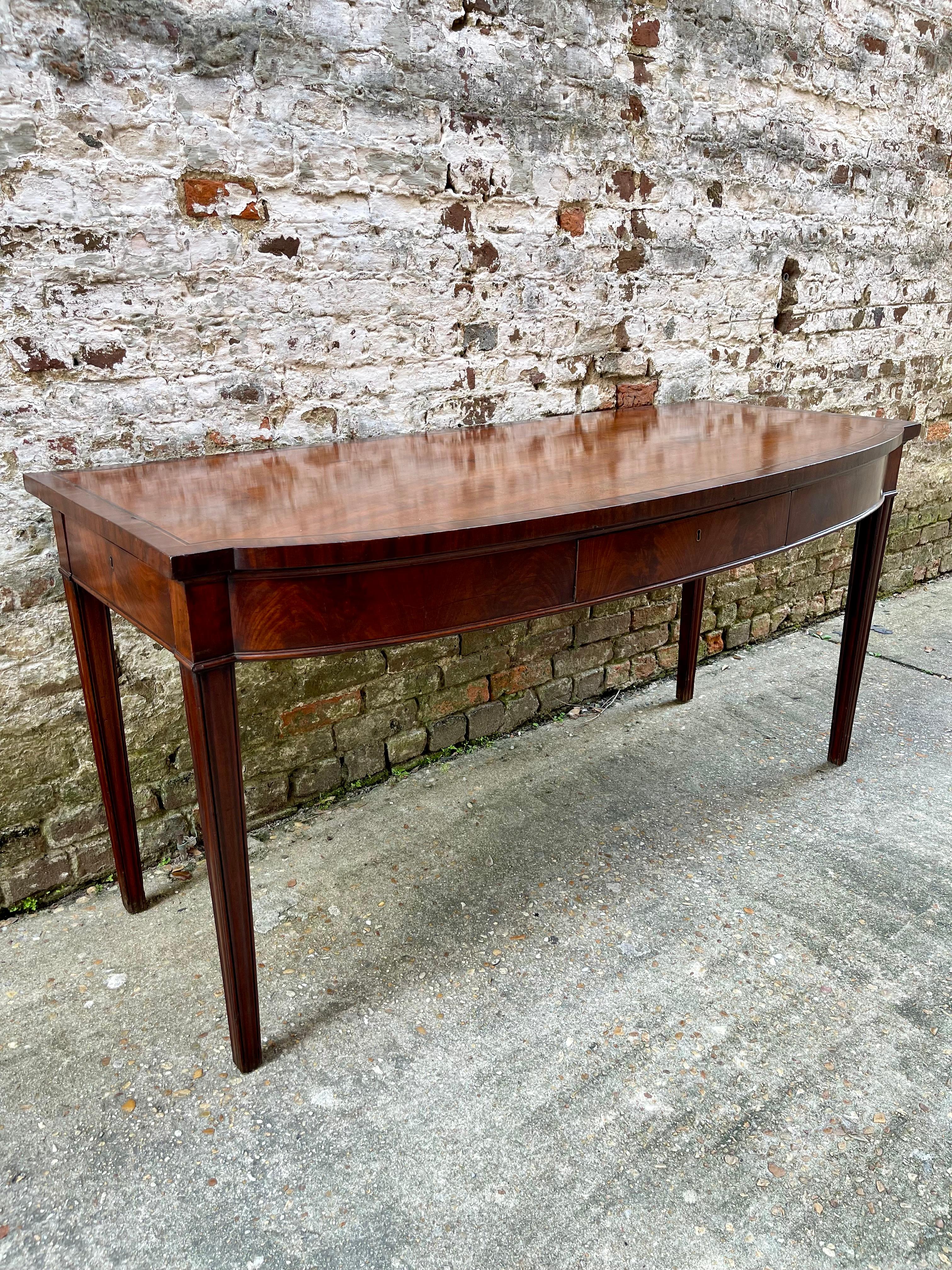 Mahogany server with tapered legs, front and two side drawers. Cross banding on top.