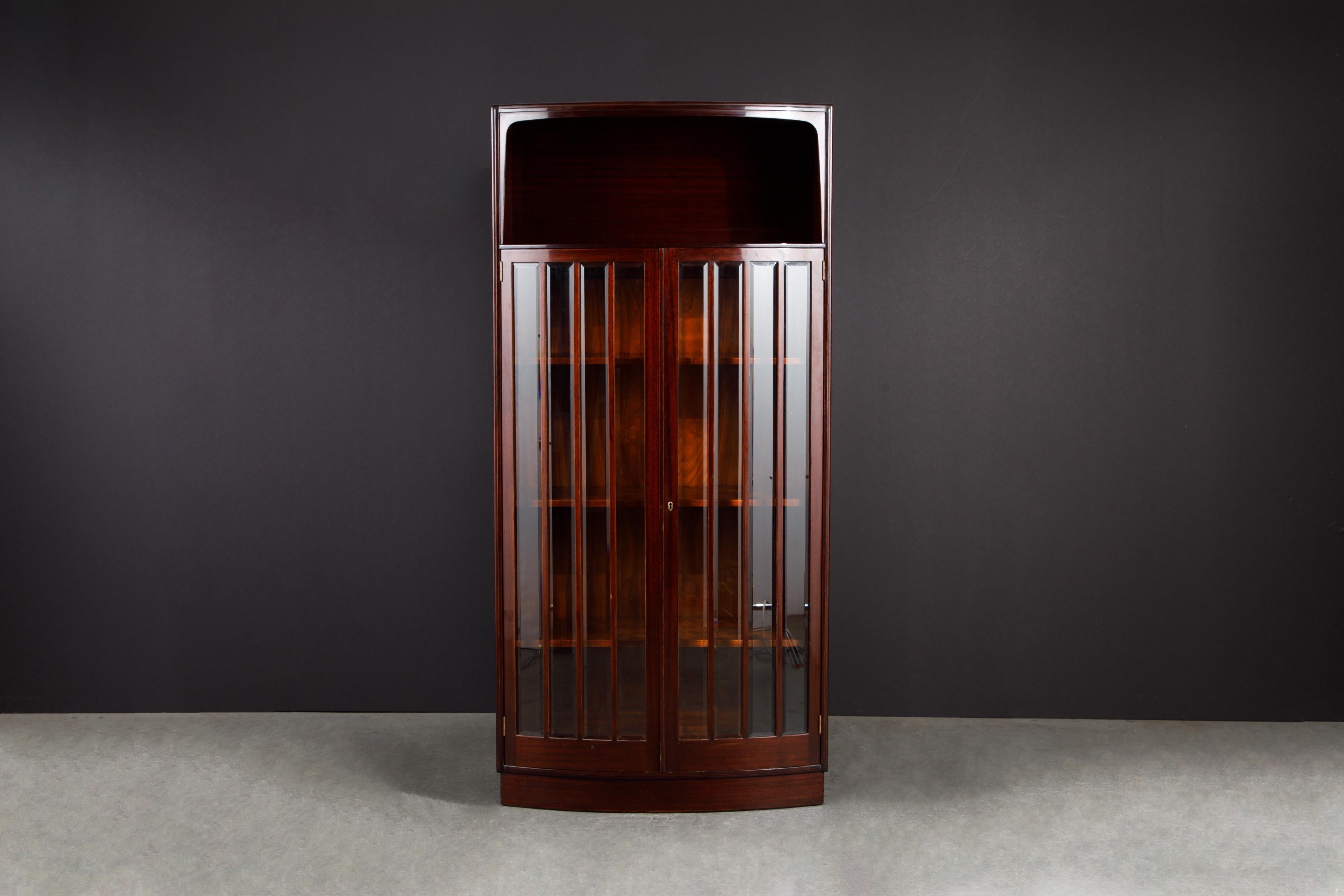 This beautiful circa 1930 art deco vitrine cabinet was constructed in gorgeous deep brown Mahogany, featuring a bowfront design with beveled glass for door panes and adjustable / removable wood shelves. Quality shelf brackets on the interior help to