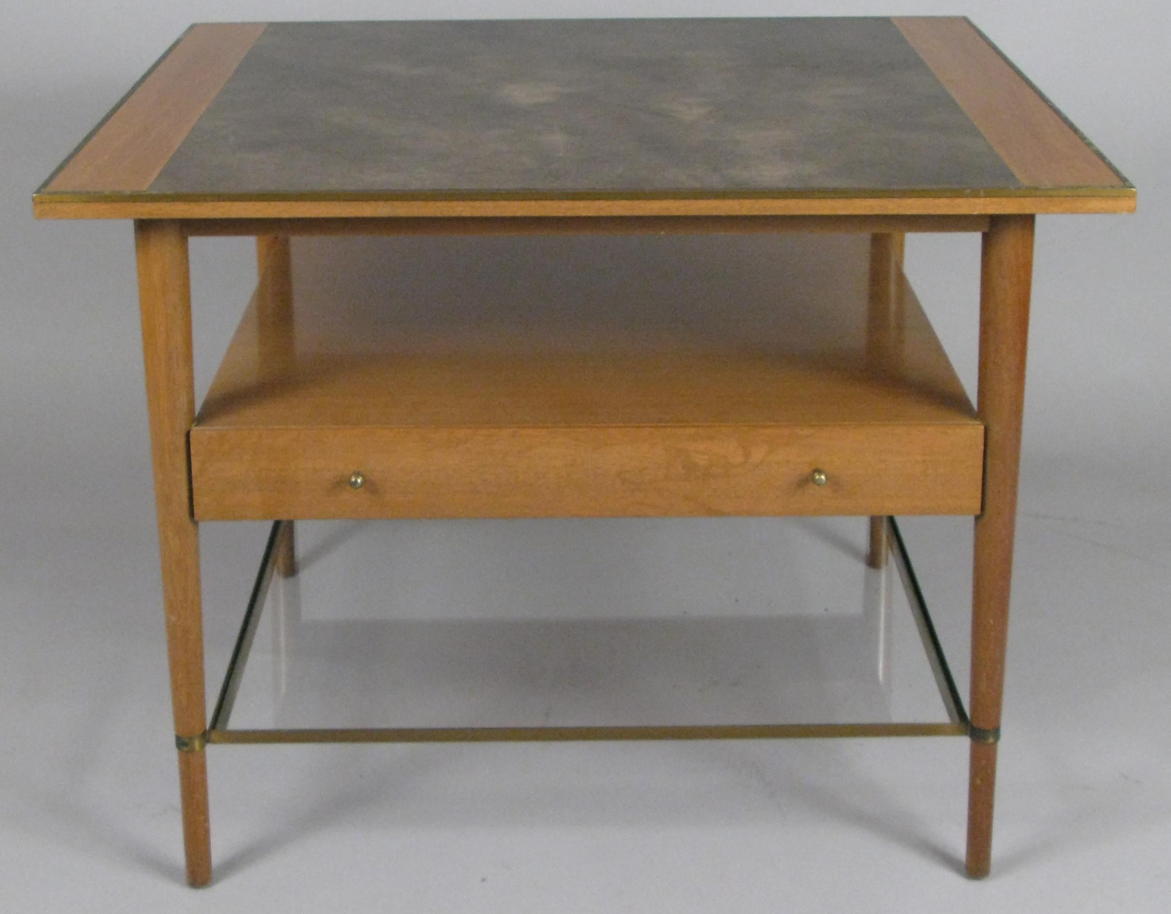 a very handsome vintage 1950s lamp table or nightstand designed by Paul McCobb. Generously scaled with mahogany case, brass trim and stretcher, a leather top, full width drawer, and lower glass shelf. Wonderful design for a variety of uses.