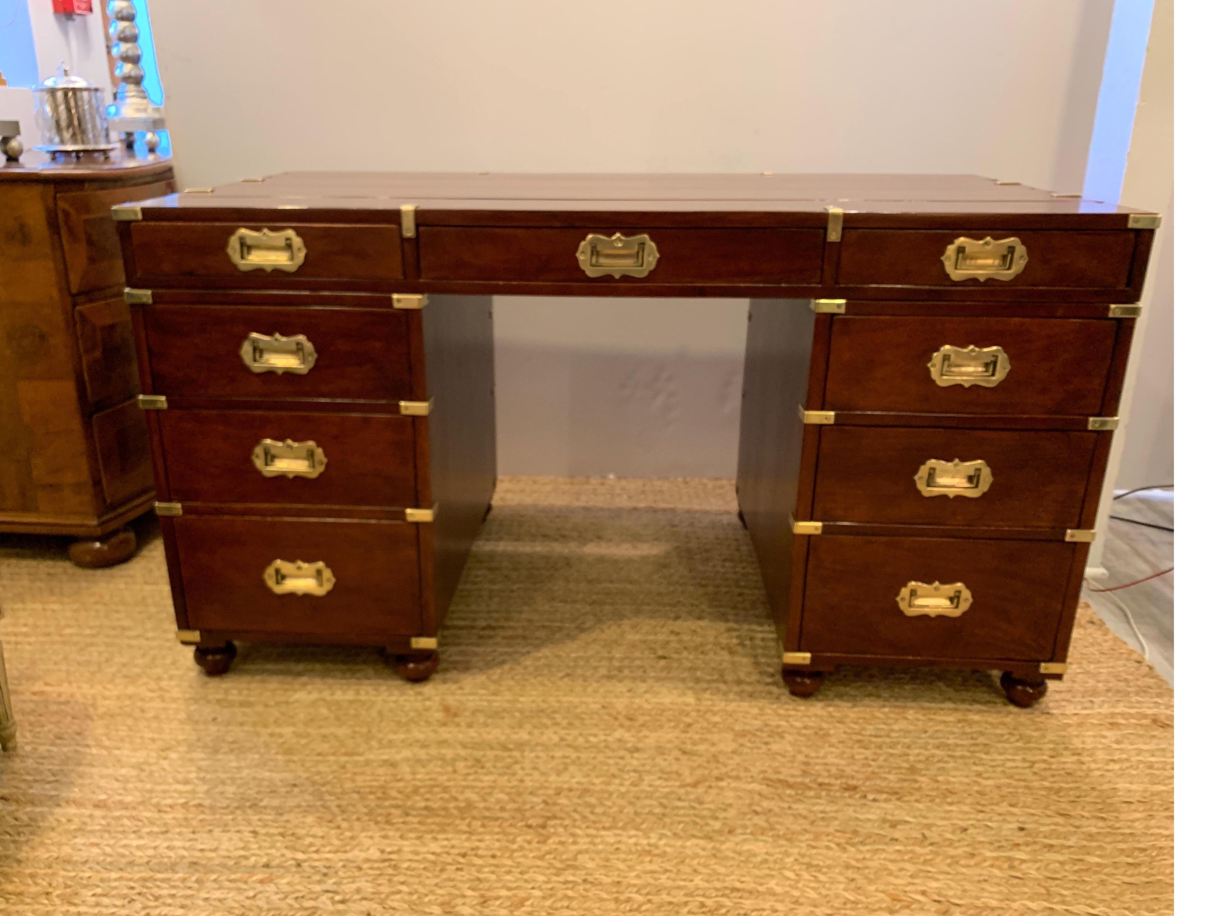 Classic campaign style double pedestal desk with brass mounts. The planked top with recent French polish, with dovetailed drawers and burnished brass handles and corner mounts. The desk has working drawers on the front and non working drawers on the