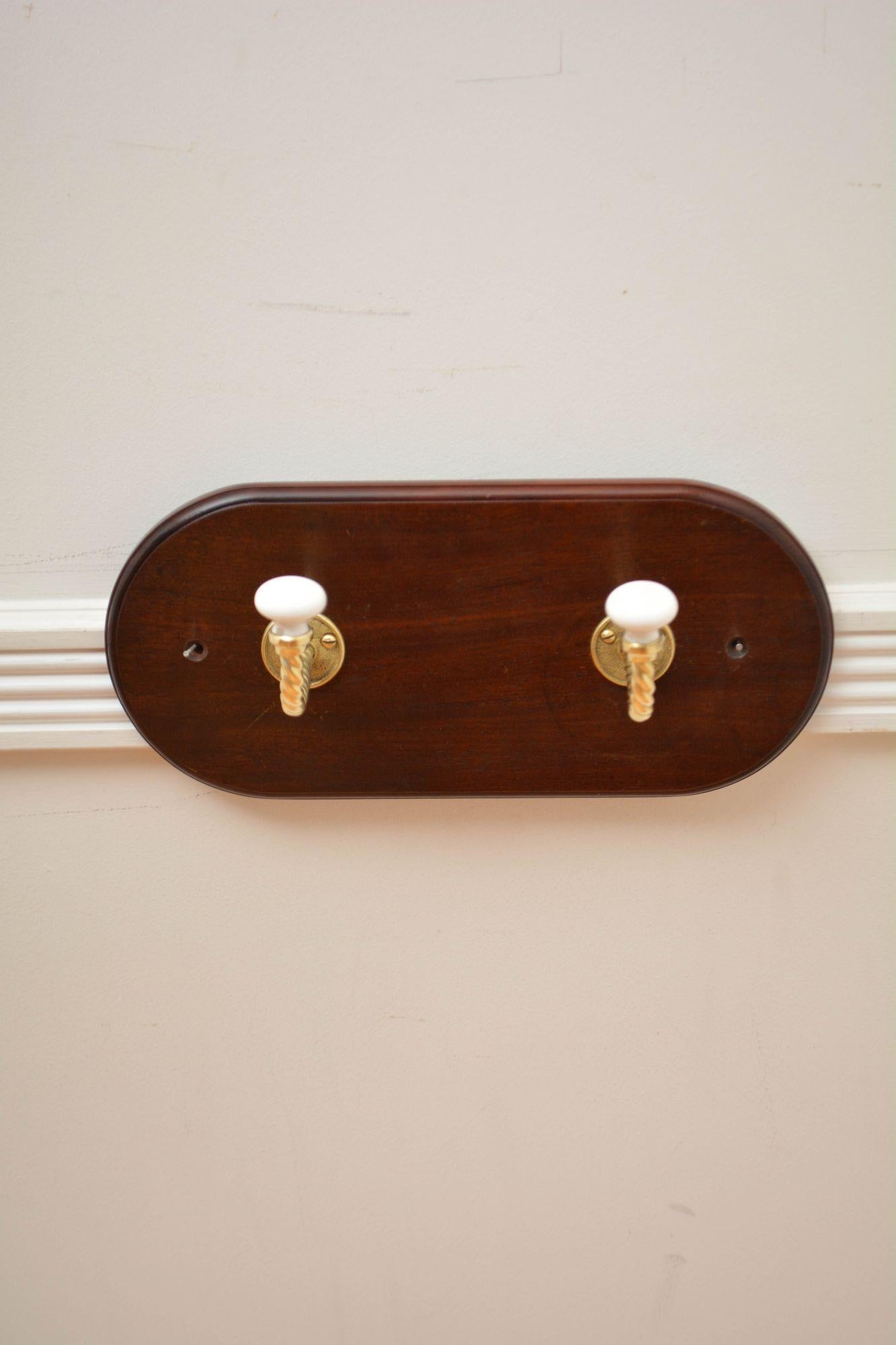 K0309 Pair of very stylish brass, twisted rope and ceramic coat hooks on solid mahogany board with moulded edge. All cleaned and polished and ready to use at home. c1880
H6 1/4