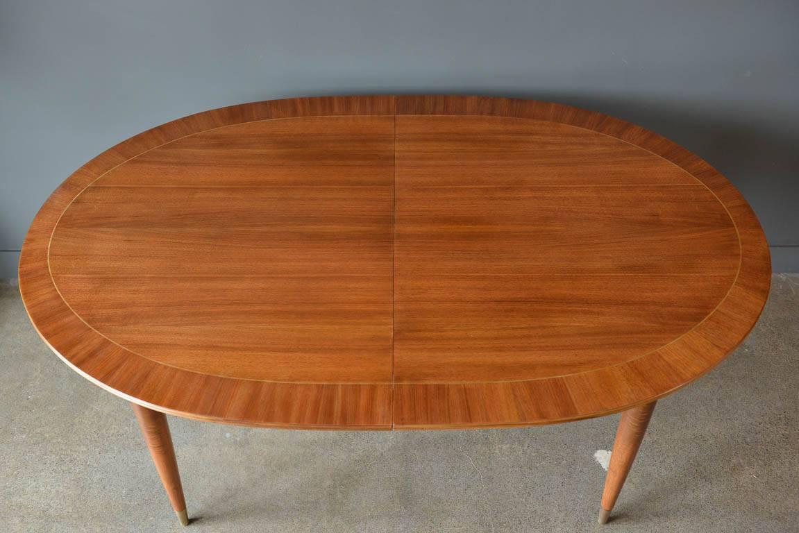 Elegant and refined design by Erno Fabry, Germany. Perfectly refinish mahogany with a brass inlay trim on tapering brass capped legs. This piece extends from 66