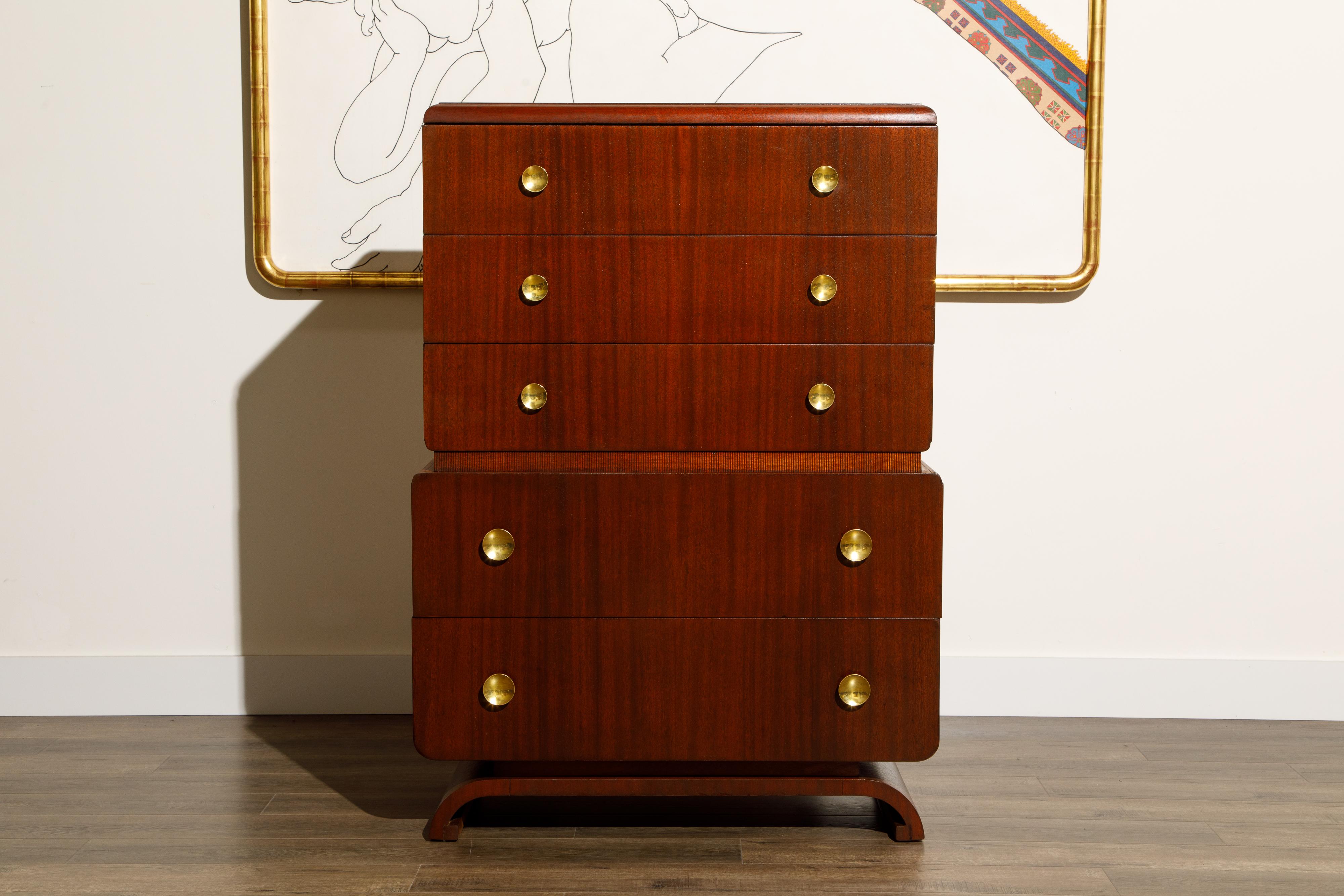 This beautiful circa 1940s restored highboy dresser by John Stuart Inc, New York, was just refinished and features a floating design with rounded edges and five drawers, each drawer with two large round brass pulls. Signed on the top drawer with the
