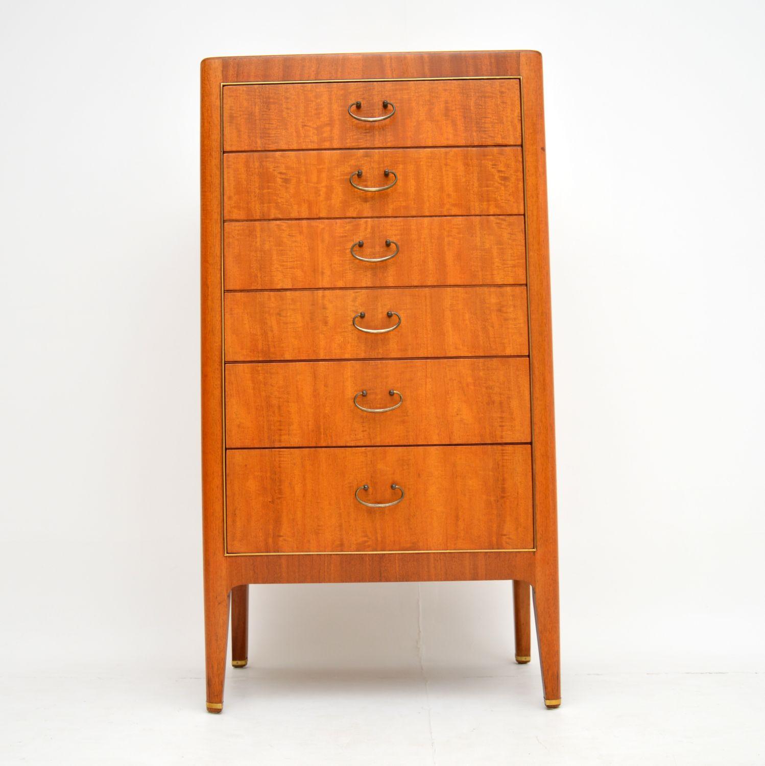 A stunning vintage tallboy chest of drawers, this dates from the 1950s. It is beautifully made from mahogany, with brass handles, a brass trim around the front edge and brass trim around the feet. This offers lots of storage space, in a sleek and