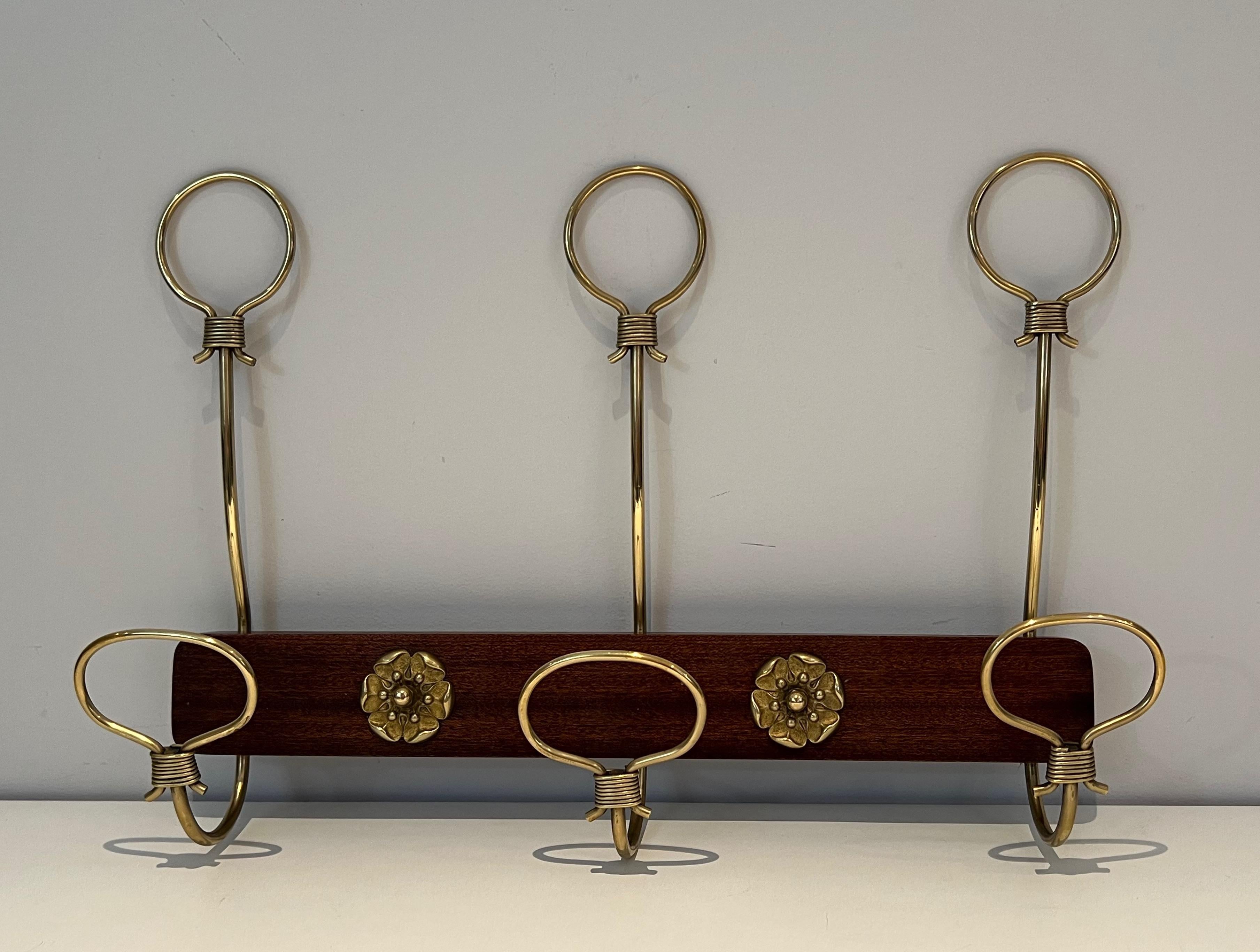 This very nice and elegants wall-mounted coat rack is made of mahogany and brass. This is a French work. Circa 1940