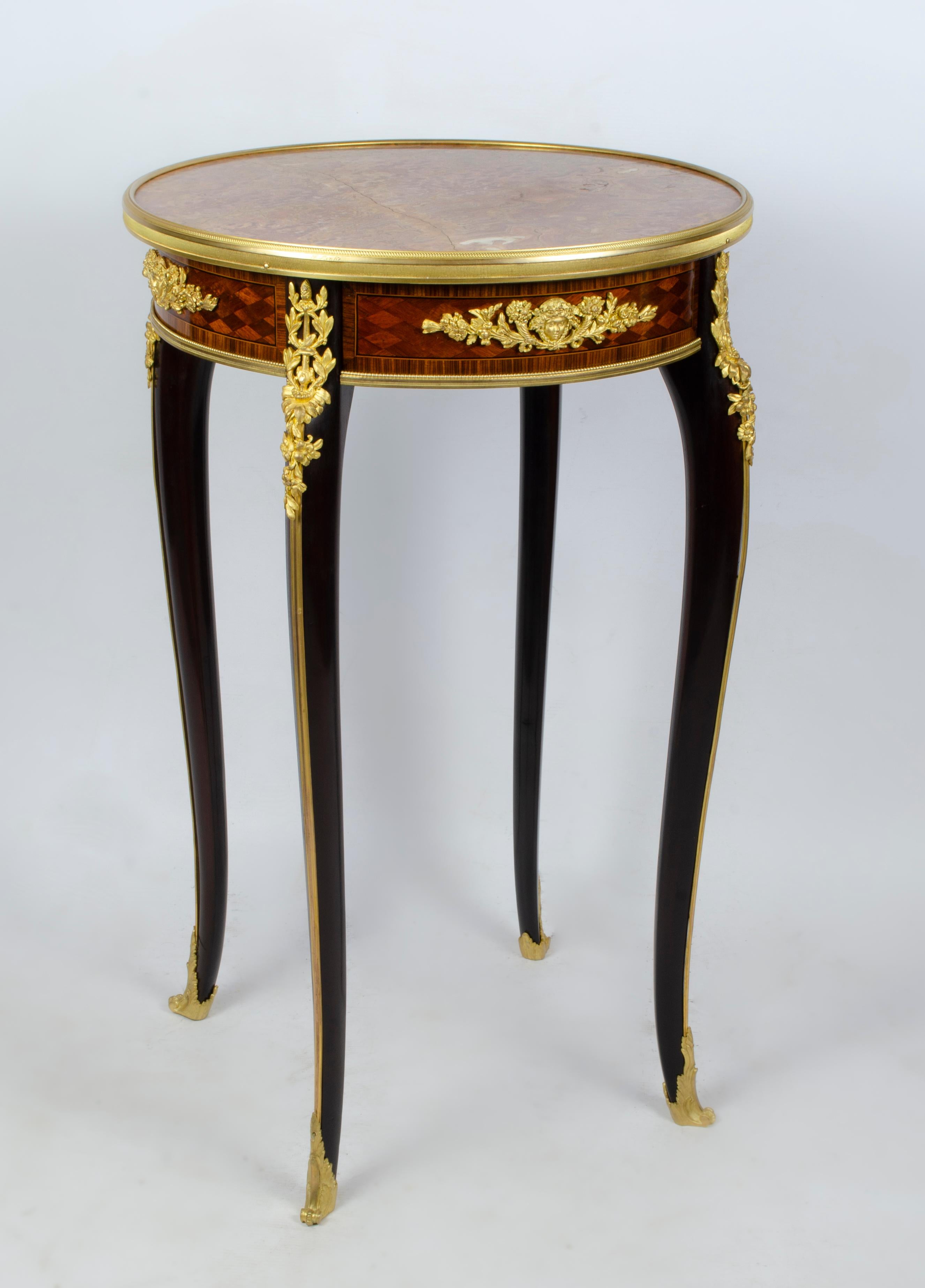 Mahogany Gueridon with a European marble top and gilt bronze inlays on a lozenge parquet frieze centered by a flanked gilt bronze mask and flowers emitting a cornucopia. The table is raised on hipped cabriole legs topped by finely cast gilt bronze