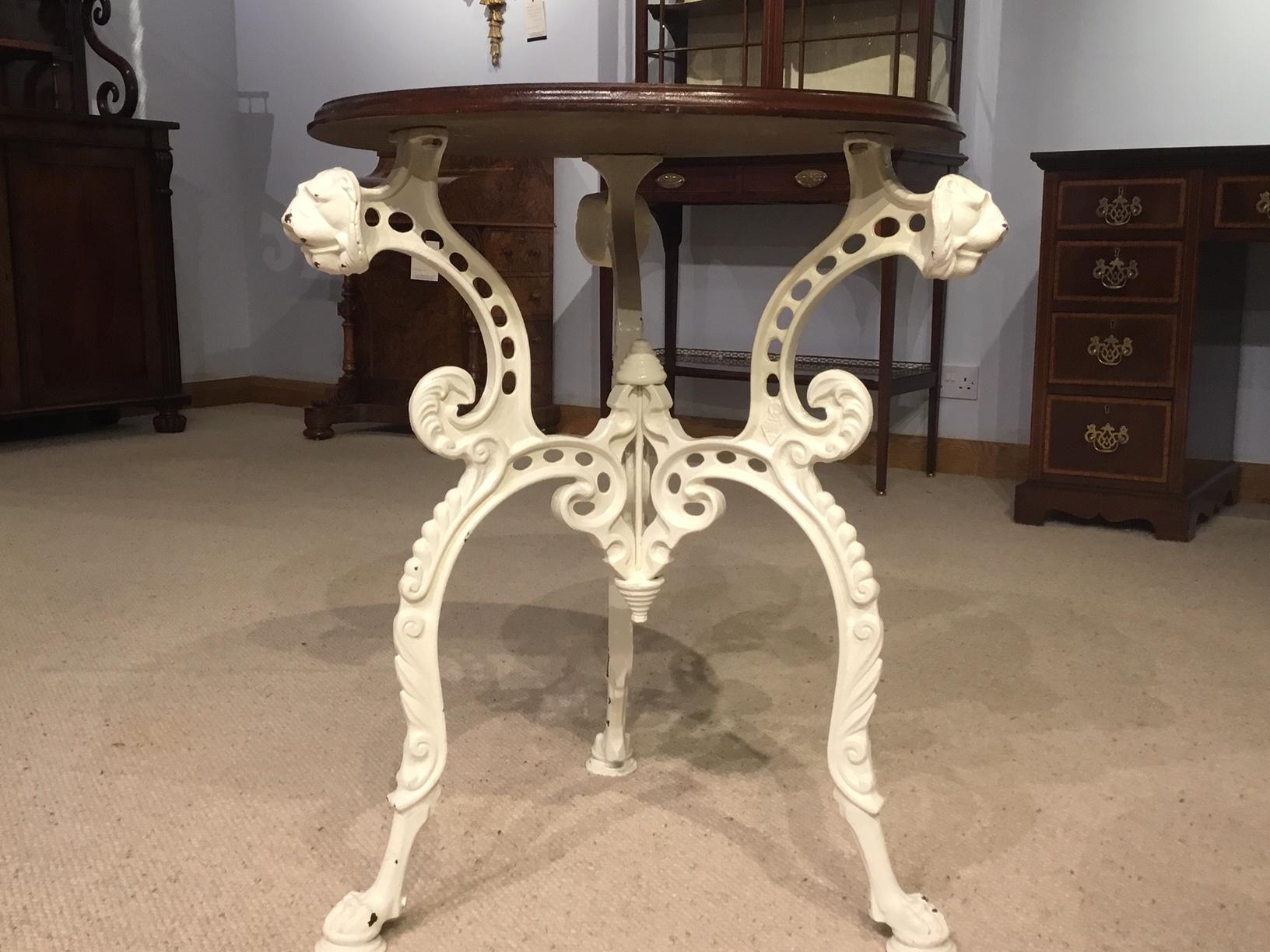 A mahogany and cast iron Victorian period pub table. Having a circular mahogany top supported on three elaborate cast iron supports with lions heads, acanthus cast detail and lions paw feet. Stamped with a Victorian kite number, possibly made by
