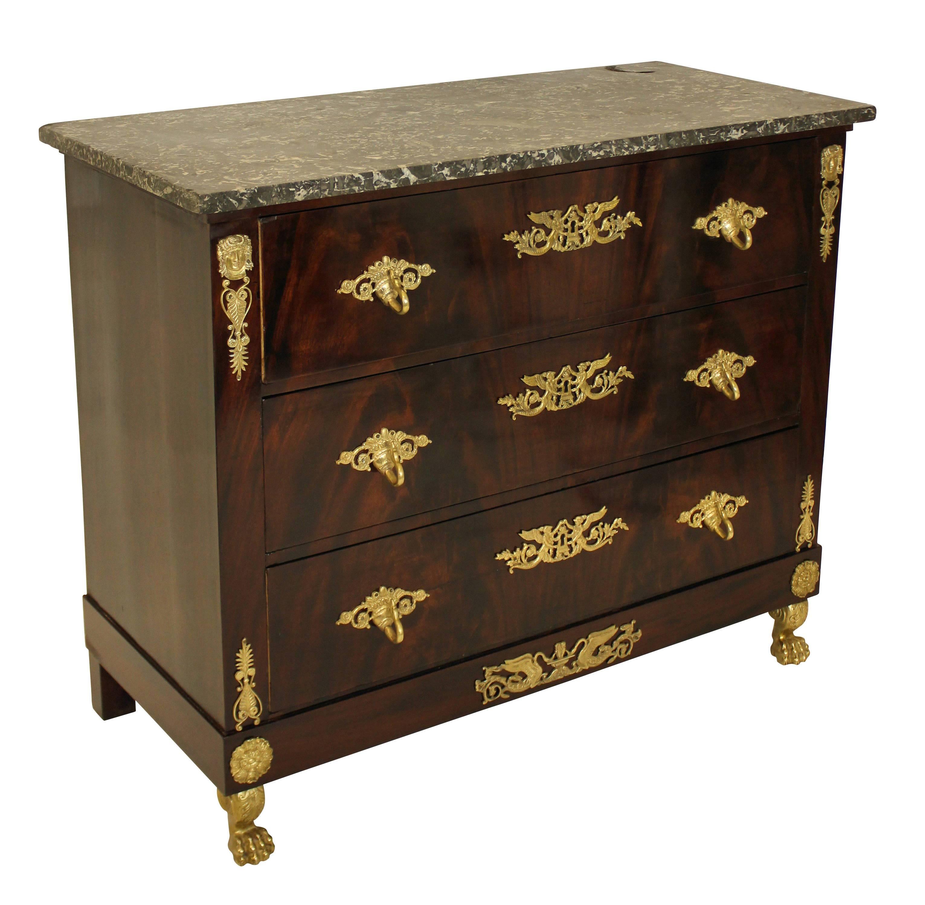 A French, first Empire commode of good quality. In flame mahogany, comprising four drawers, profusely decorated with gilt bronze mounts with detailed gilt bronze lion paw feet and a Belgian fossil marble-top.