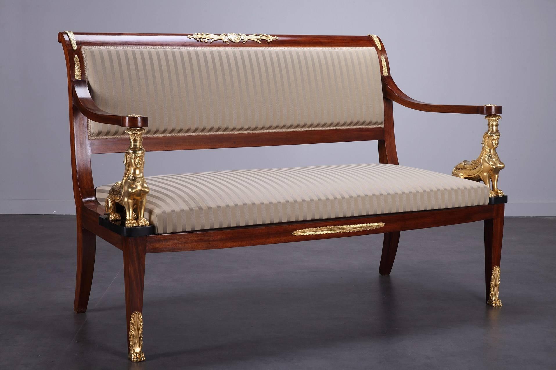 Mahogany living room set in Return from Egypt style composed of a sofa, two chairs and two armchairs. The wood framing of the sofa and armchairs is embellished with ormolu rosette and foliage. The arms are resting on sphinx and the belt is decorated