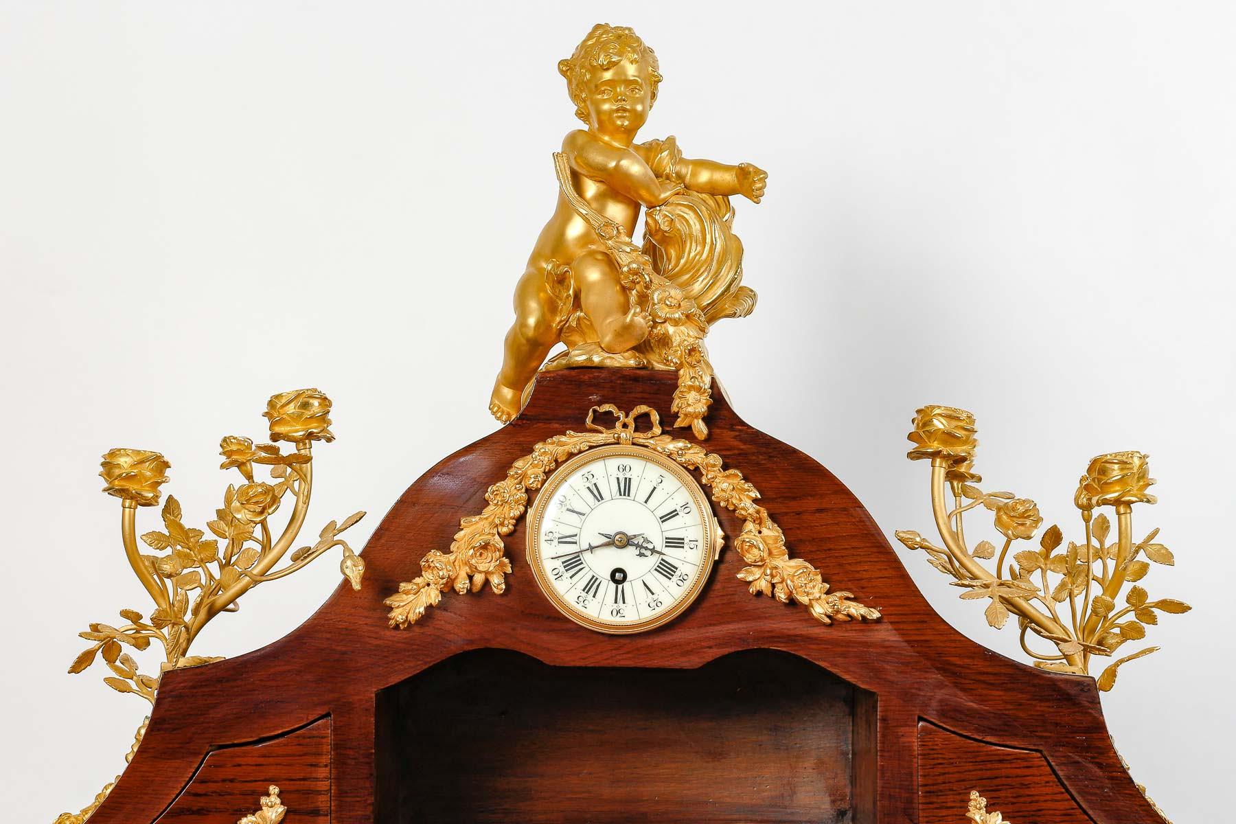 Mahogany and gilt bronze Rognon desk, Grande Décoration.

Napoleon III style Rognon desk in mahogany and gilt and chased bronze, pair of sconces on either side, surmounted by a little girl, central clock, 19th century or early 20th century, with its