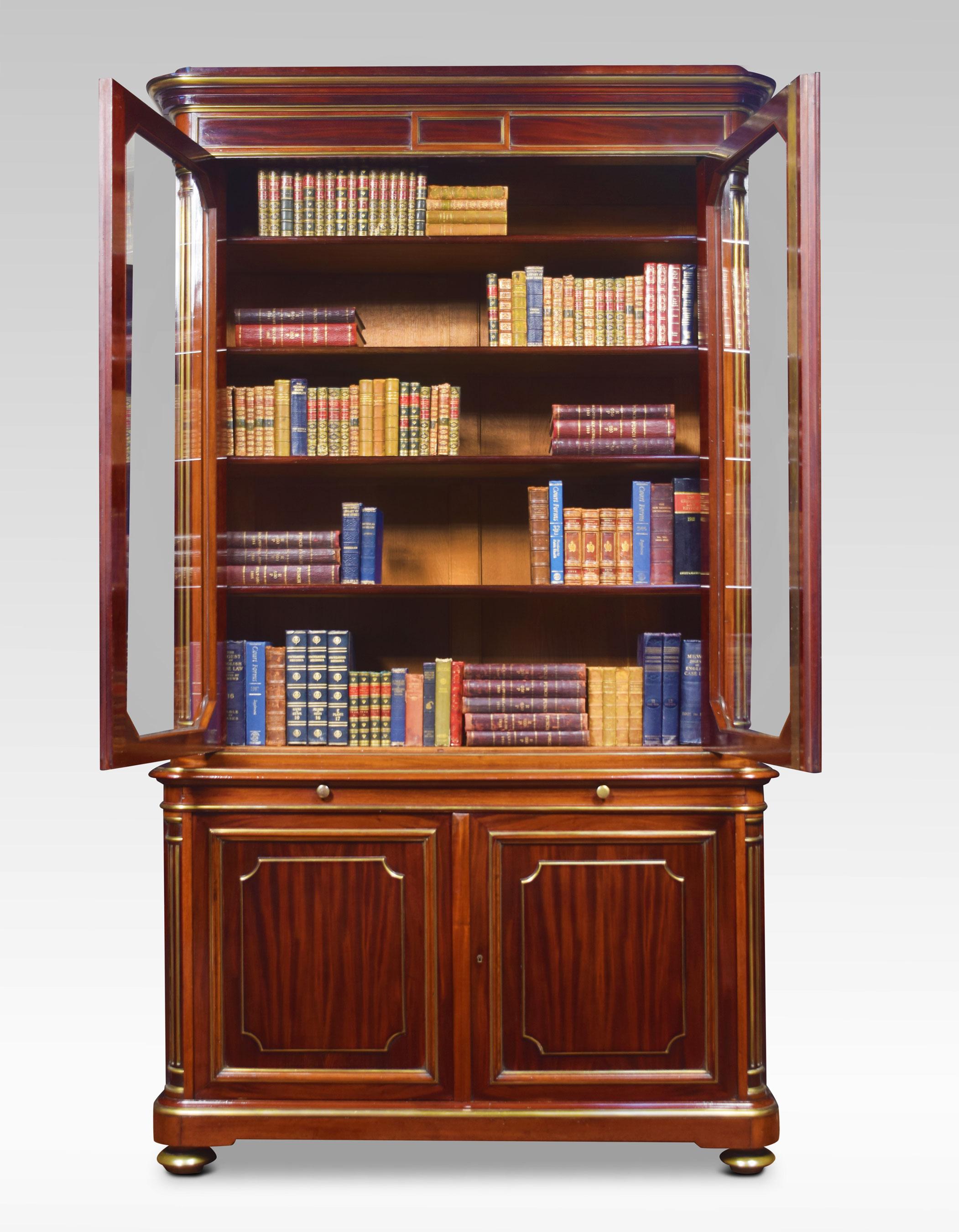 French mahogany and gilt metal mounted bookcase. The moulded cornice above a pair of glazed doors opening to reveal adjustable shelved interior above a brushing slide. The base fitted with a pair of panels doors enclosing an arrangement of sliding