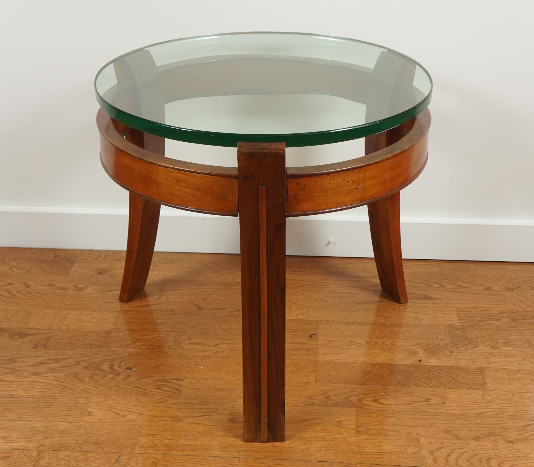 A round occasional table featuring a tripod frame in mahogany with a lowered skirt and three outward bending tapering legs.
Also features a very thick glass top.