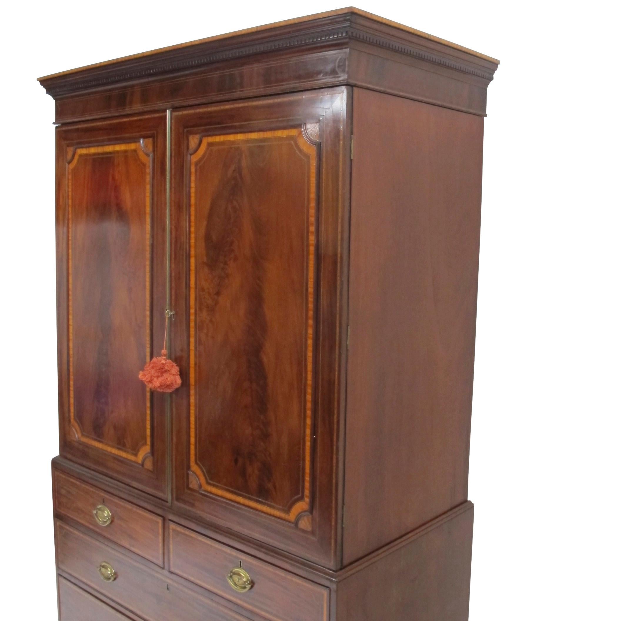 Mahogany linen press with recessed panelled doors trimmed with satinwood banding and shell shape corner medallions. The doors opening to reveal five full width open drawers, the top sitting above two shot drawers over two long drawers with matching