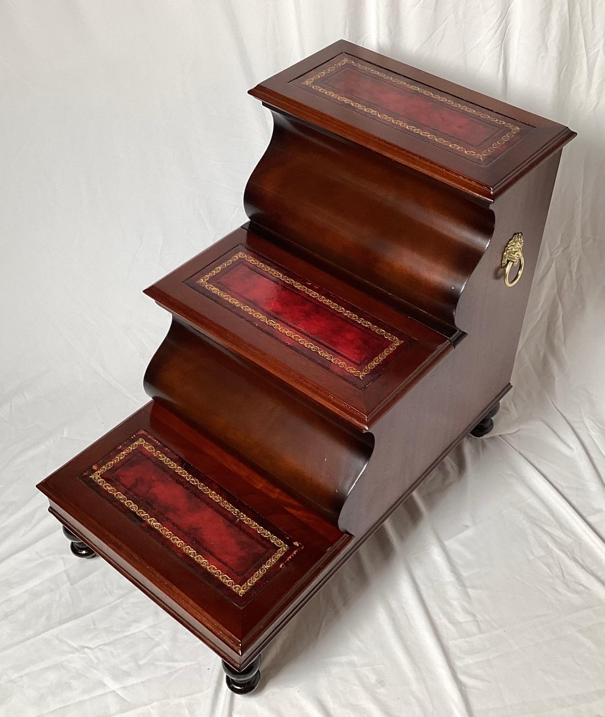 A classic set of leather and mahogany library steps with brass handles. The center stair with a lift up storage compartment. Brass Lion motif handles. These steps have recently been touched up and French Polished.