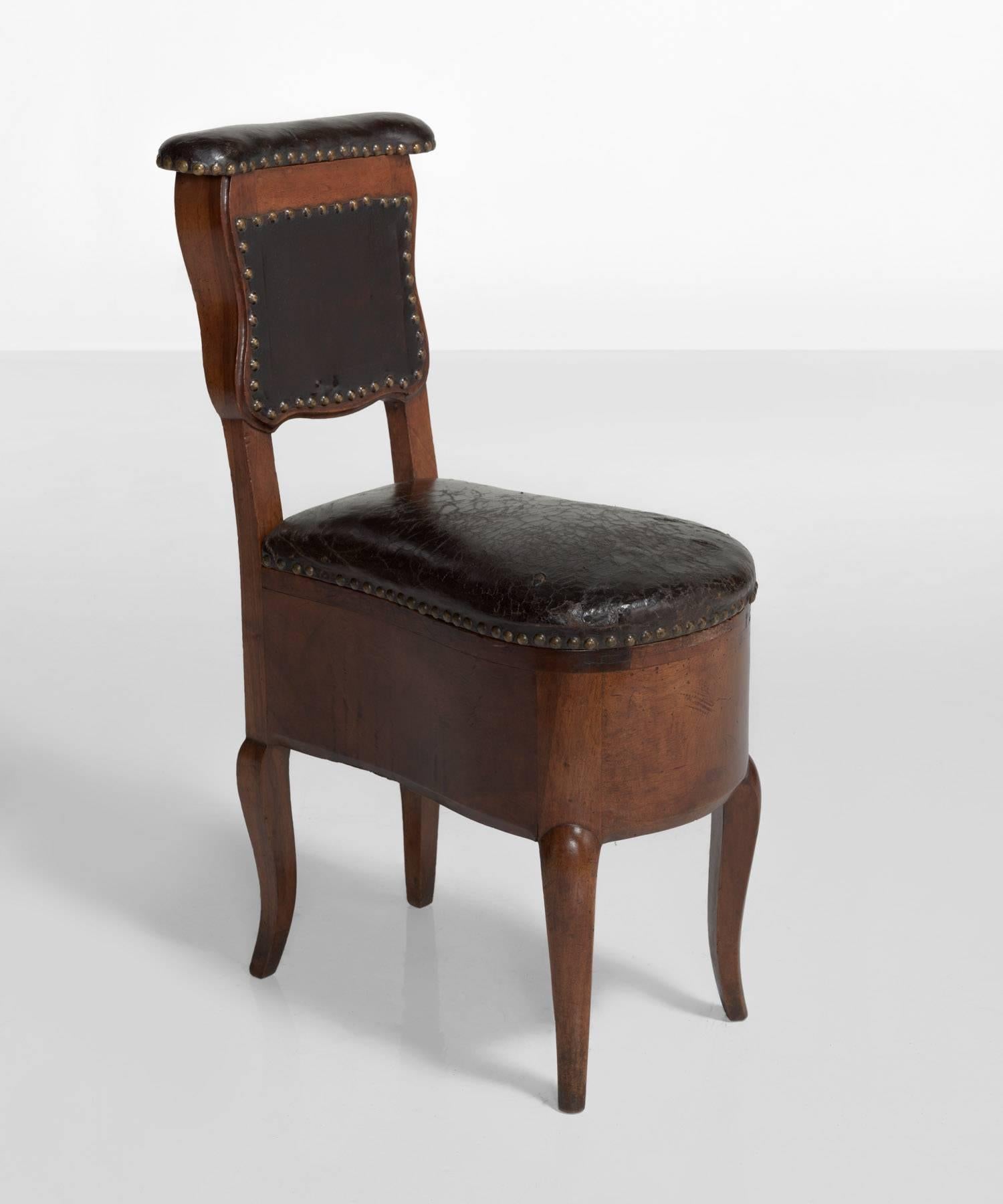 Mahogany and leather Prie Dieu chair, France, circa 1780.

Carved mahogany devotional chair with storage under seat and behind back. In original condition. Unique form. Well worn leather with brass studs.