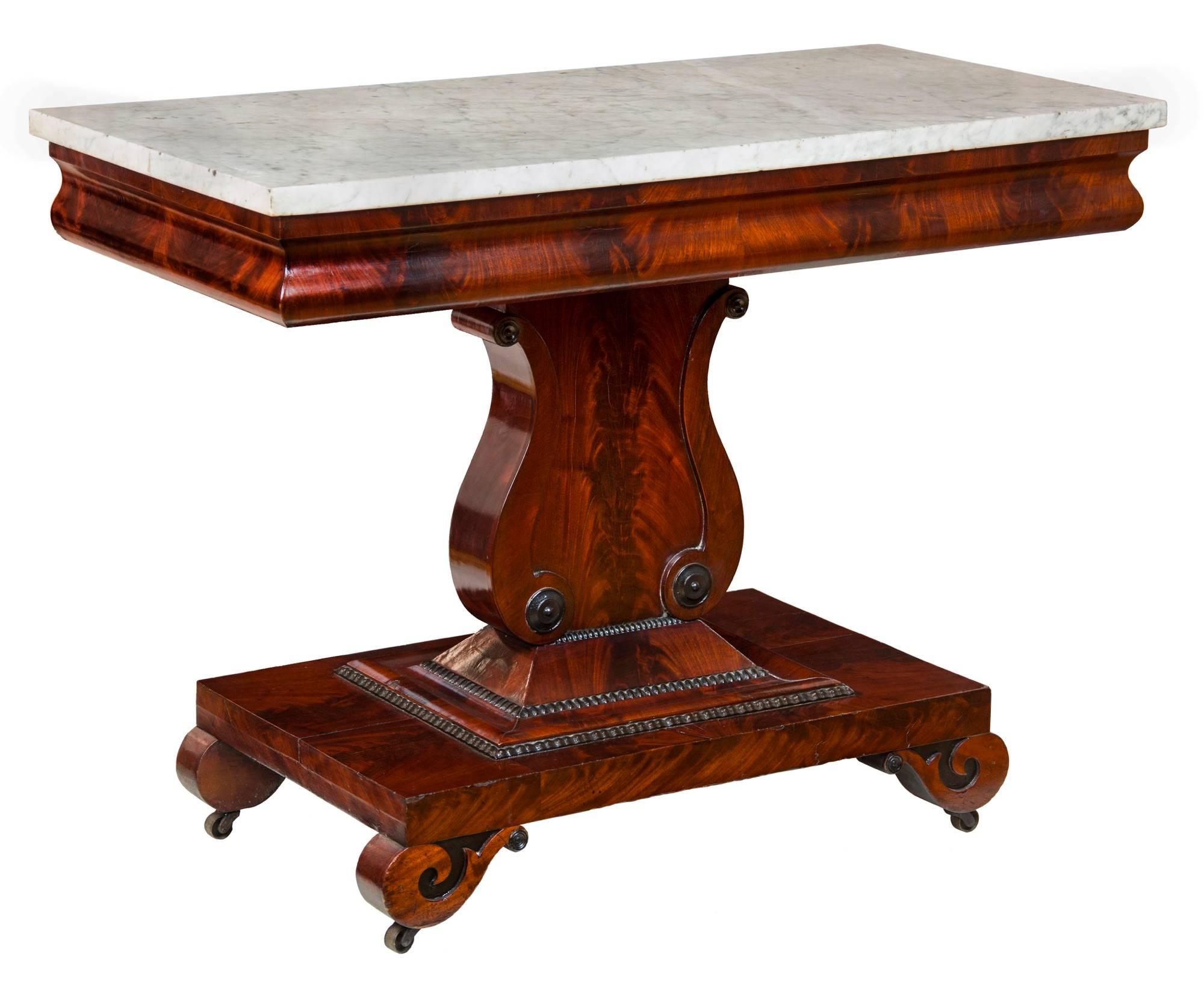 This is a vibrant side table composed of highly figured crotch grain mahogany.   Note its artful use within the center of the lyre base, and also around the apron of the top and beautiful sections on the base, or plinth.    

It is architecturally