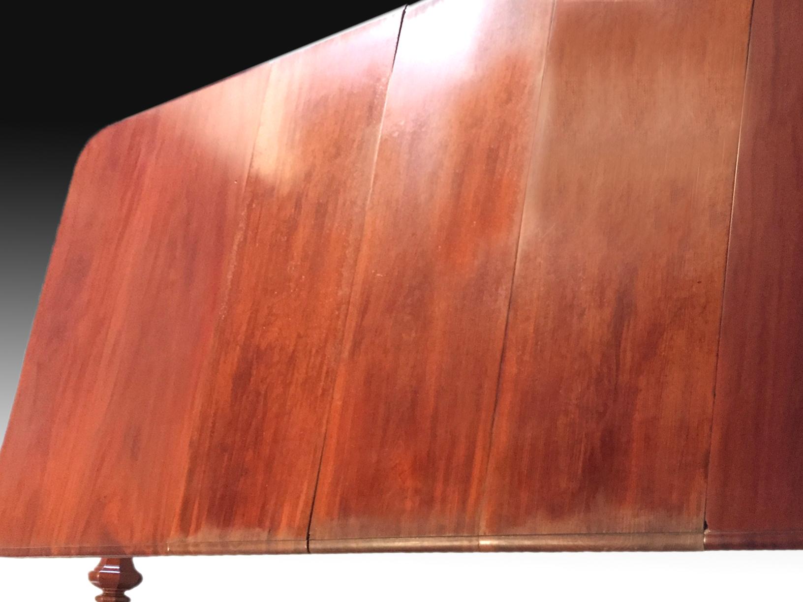 Table rectangulaire extensible par panneaux et système mécanique actionné manuellement par manivelle, réalisée en bois d'acajou sculpté et éléments métalliques (extrémités des pieds, mécanisme, réas). Le plateau supérieur a été laissé lisse, avec un