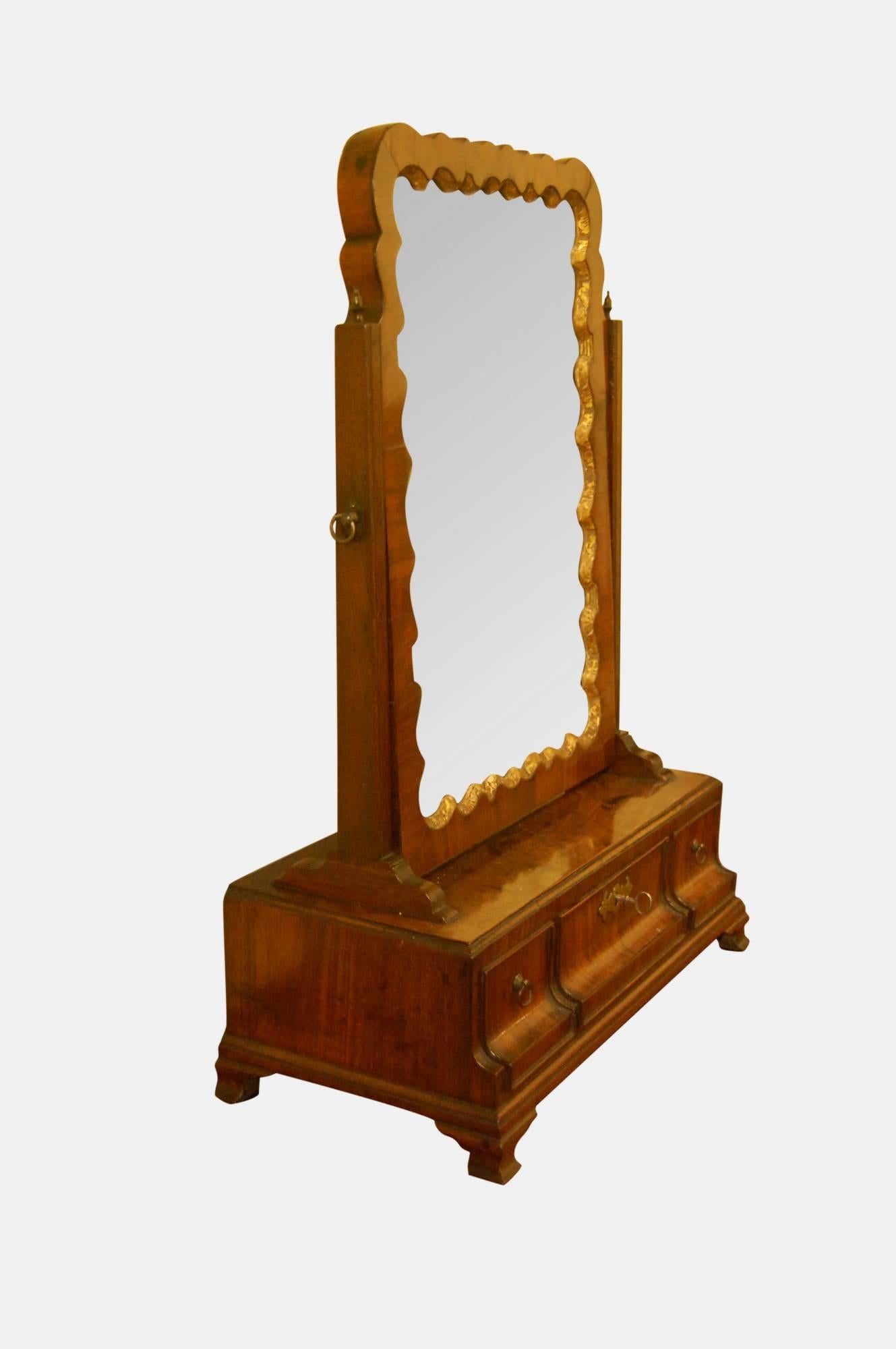 Mid-18th century mahogany and parcel gilt toilet glass

The three-drawer concave base raised on ogee feet

Mirror has serpentine carved gilt slip with original plate.