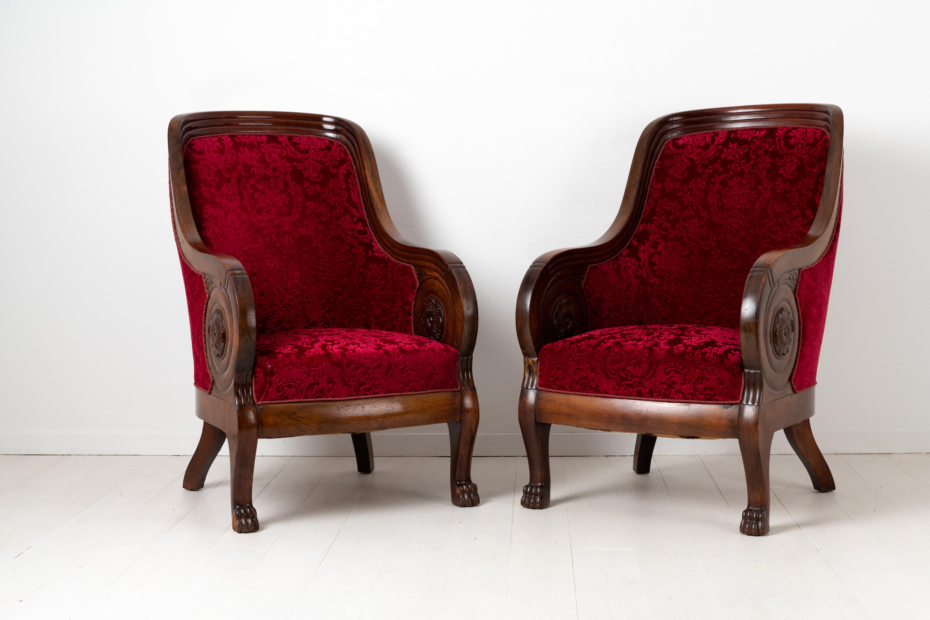 Pair of mahogany armchairs in Empire style. The chairs are from the late 1800s and are most likely from the Baltic. Upholstery in red velvet with curled armrests.
  