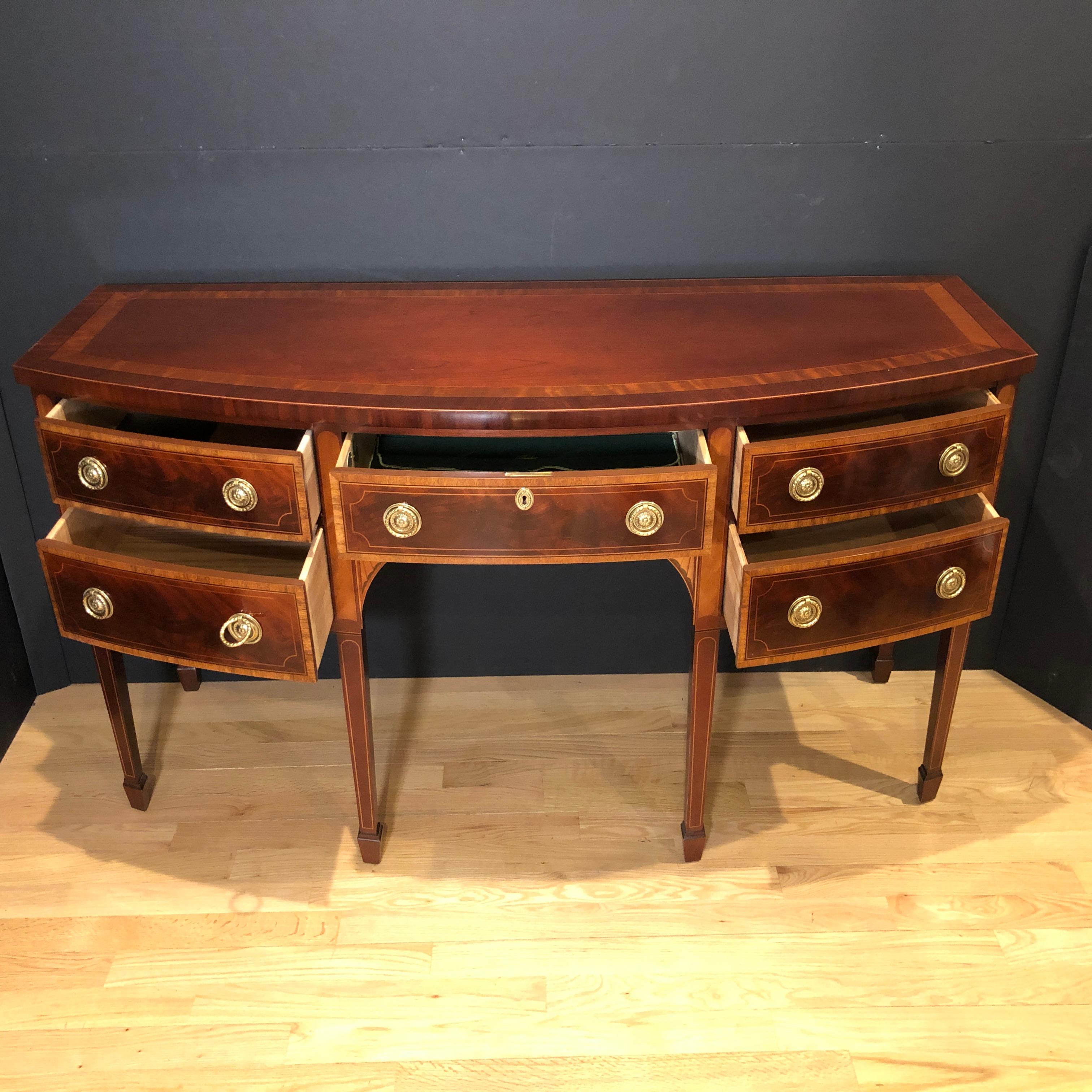 Mahogany and satinwood inlaid bow front sideboard by Baker Historic collection. This fine custom quality sideboard is made by arguably one of the finest American furniture makers. Baker Furniture Company produced this Hepplewhite inspired sideboard