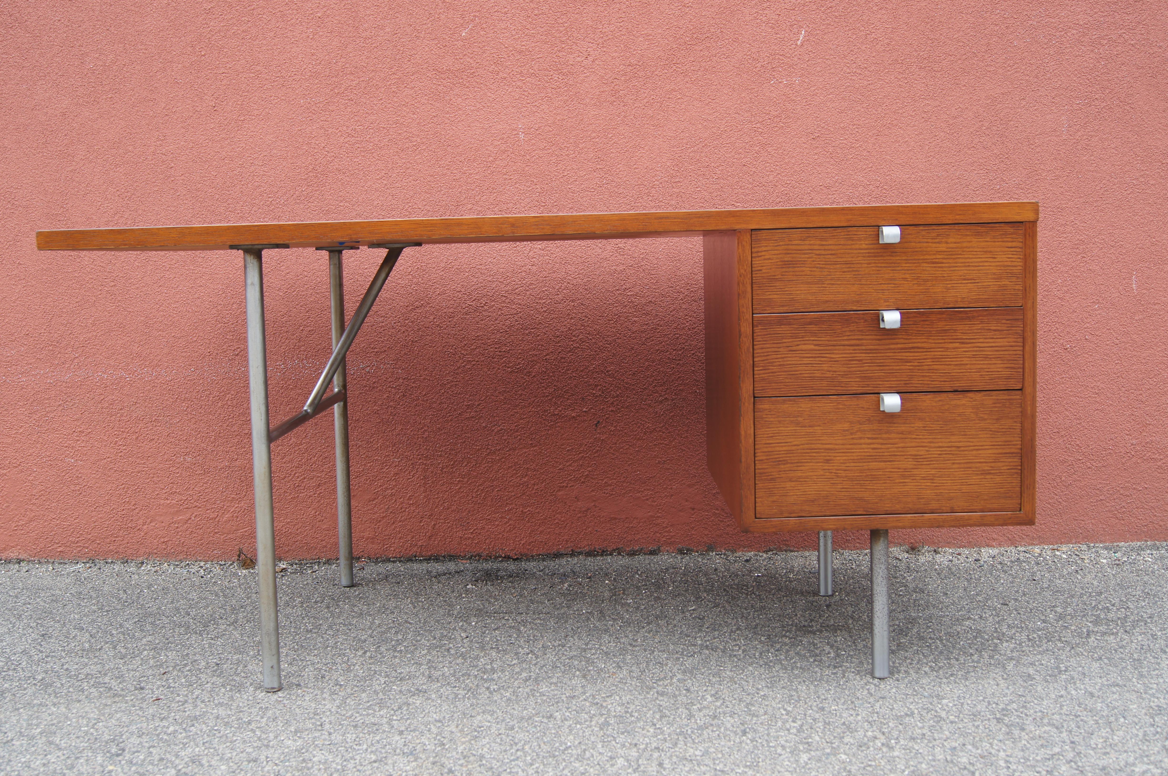 George Nelson designed this modern desk for Herman Miller. A steel frame supports a beautifully grained mahogany top cantilevered at one end and, on the other, a small case housing three drawers with J-shaped pulls.
  