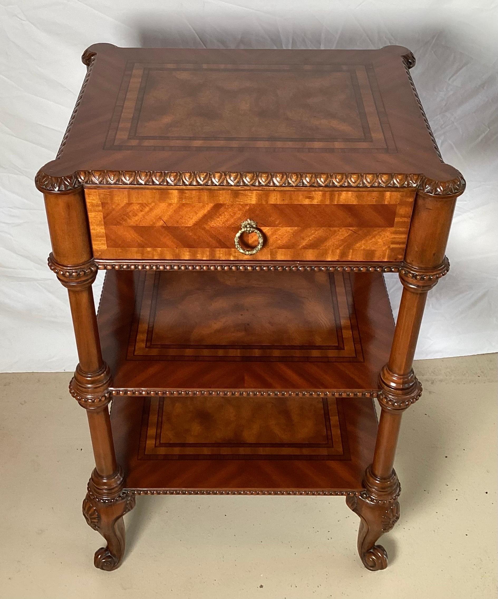 Elegant tiered accent table with top drawer by Maitland Smith. The drawer with two shelves under, supported by carve mahogany cabriole legs. The top with beautiful matched inlays of burl and mahogany. The top with egg and dart carving on the edge.