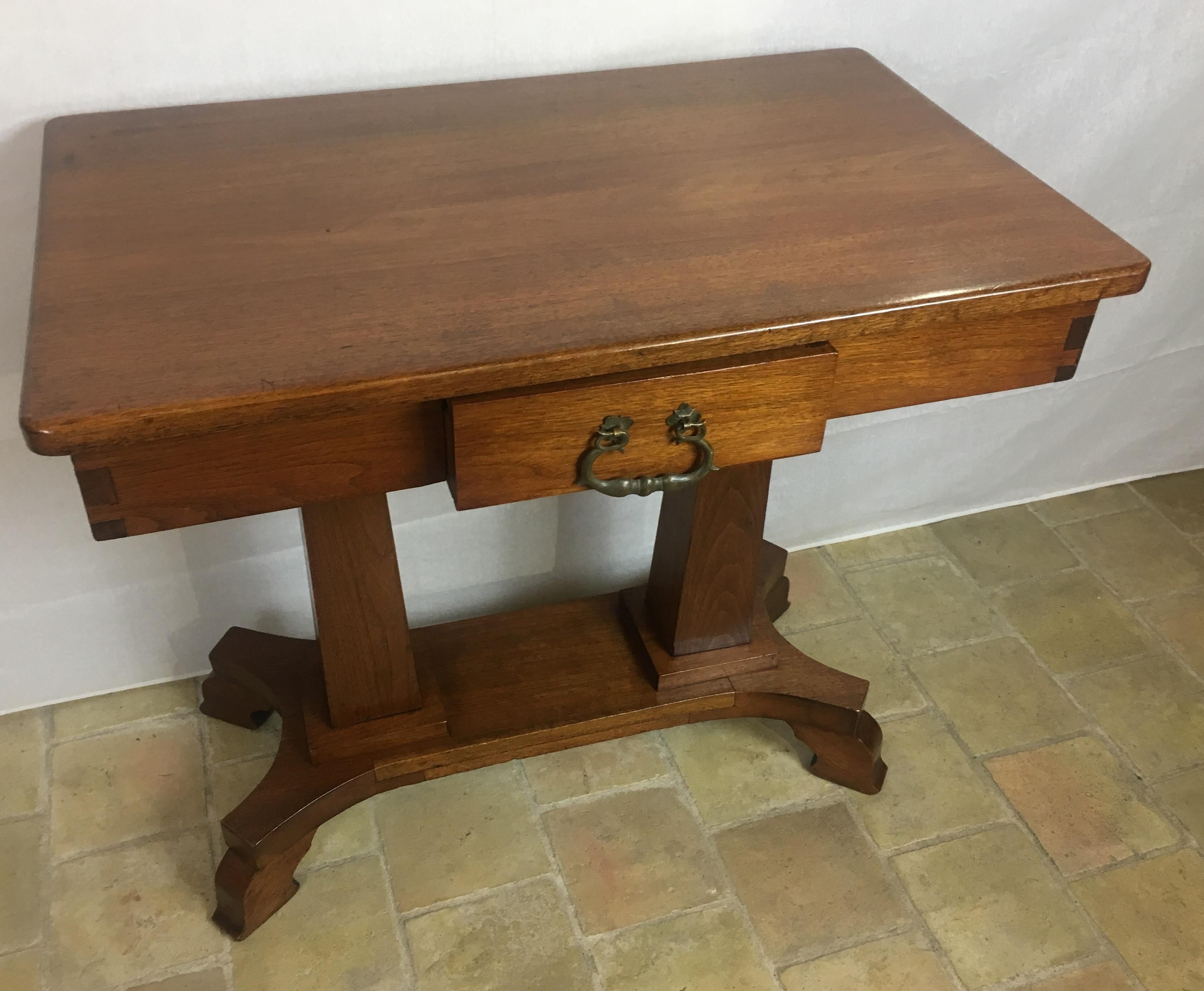 Iconic American arts and crafts table with a bold simple form which marked the era and this handsome table/desk is exemplary of the movement.  It is constructed of fine mahogany wood and has a single drawer has brass ornamentation. 

This is a