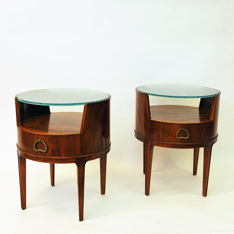 Lovely pair of round nightstands or side tables designed by Axel Larsson in the 1940s produced by Bodafors in Sweden. Dark mahogany with round tinted glass table tops with etched square patterns. Sculpted drawers and beautifully designed brass