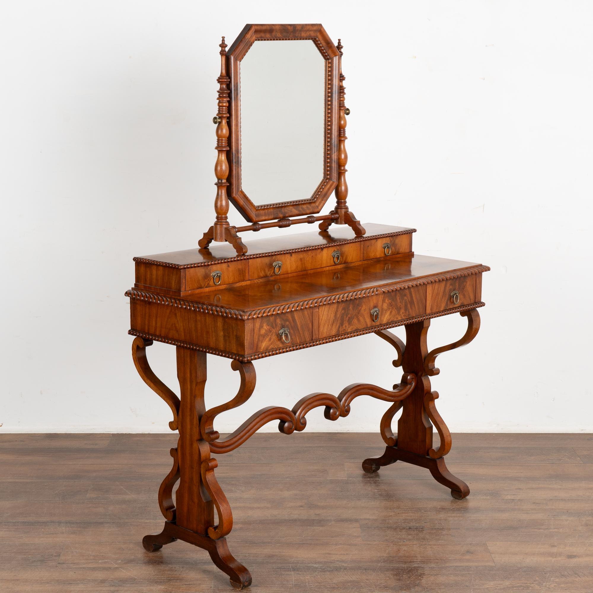 Decorative biedermeier mahogany vanity or dressing table with mirror.
Six drawers, adjustable mirror (which can be removed from table top, see photos), and decorative carved legs and base.
Restored, stable and ready for use. 
Any scratches, cracks,