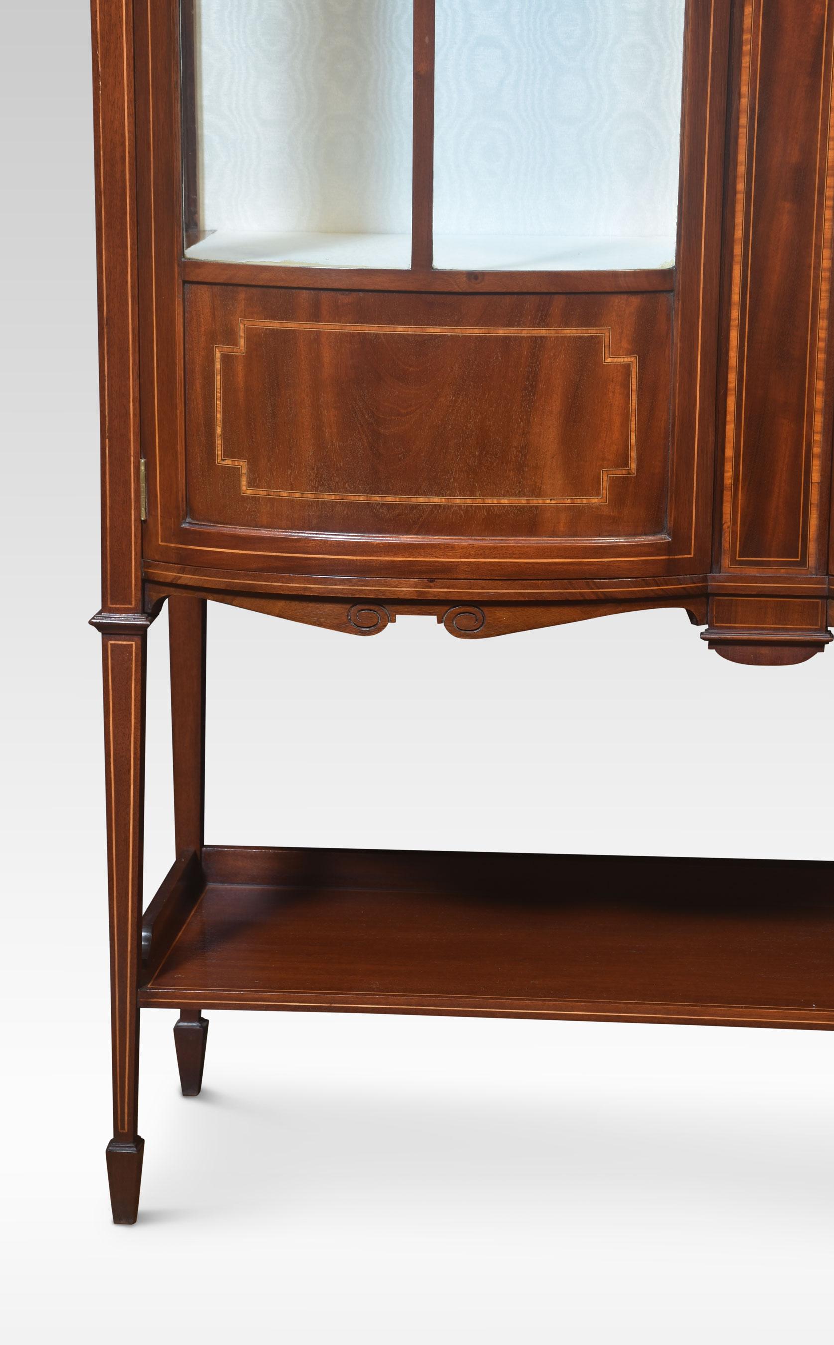 Mahogany bow front display cabinet. Having a pair of glazed doors enclosing shelved and watermark silk upholstered interior, flanked by glazed ends. All raised up on tapering supports united by under tier.
Dimensions
Height 70 Inches
Width 48