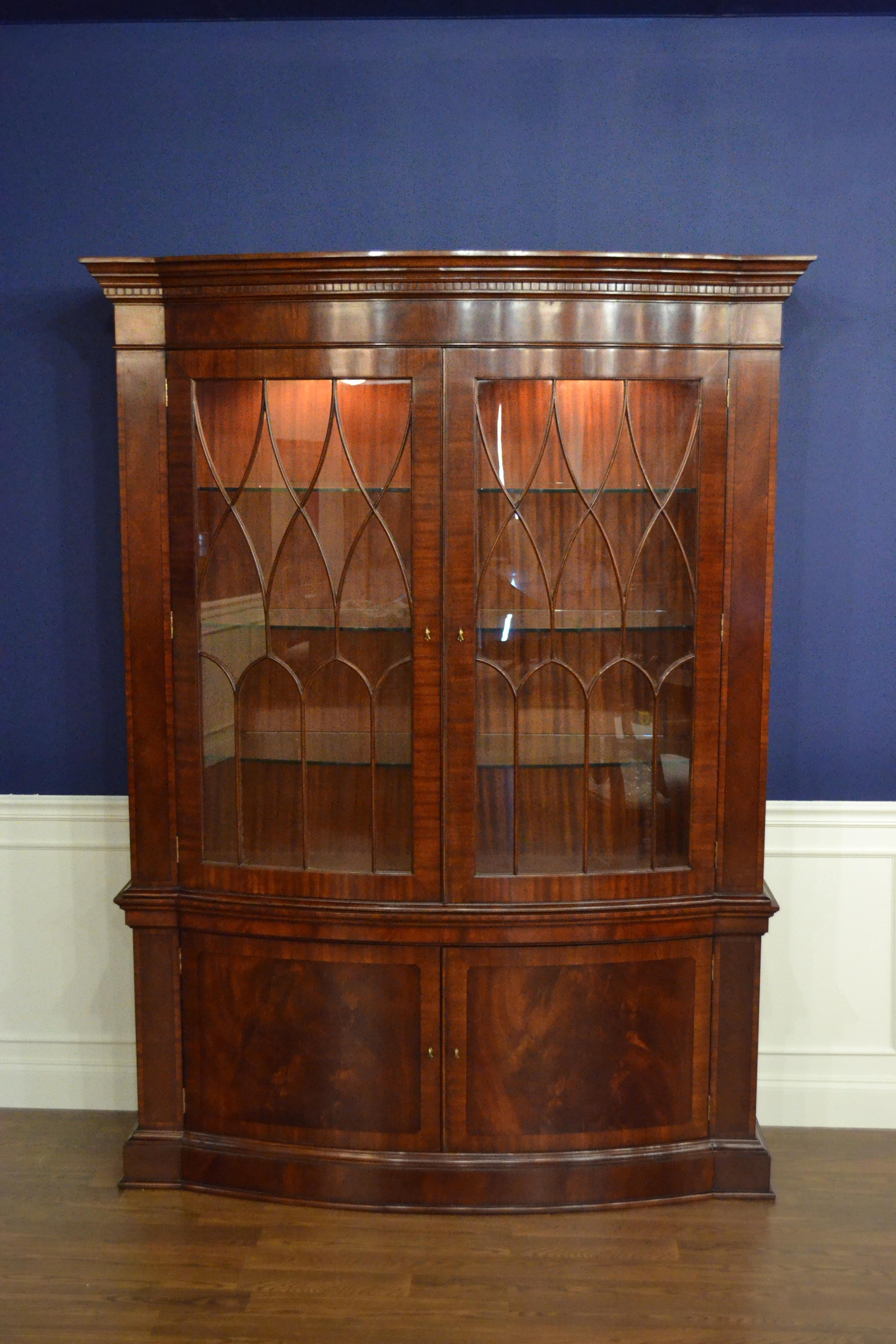 This a traditional mahogany bow front display or china cabinet with two doors by Leighton Hall. It features a delicately bowed front shape. The cabinet features two bottom doors with swirly crotch mahogany fields and straight grain mahogany borders.