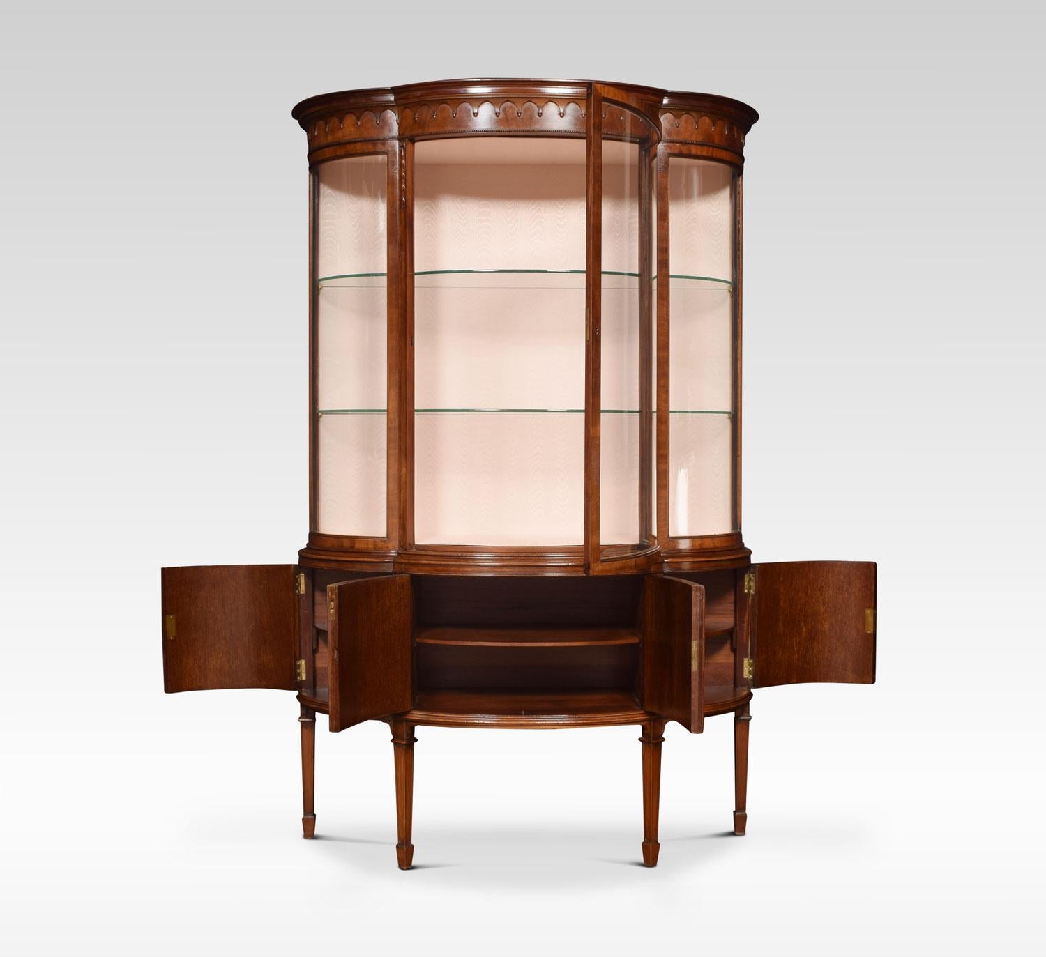 Mahogany display cabinet the moulded cornice above large curved glazed door flanked by two bowed sides. The interior having water mark silk back and two glass shelves. The base section having four flame mahogany panelled doors all raised up on