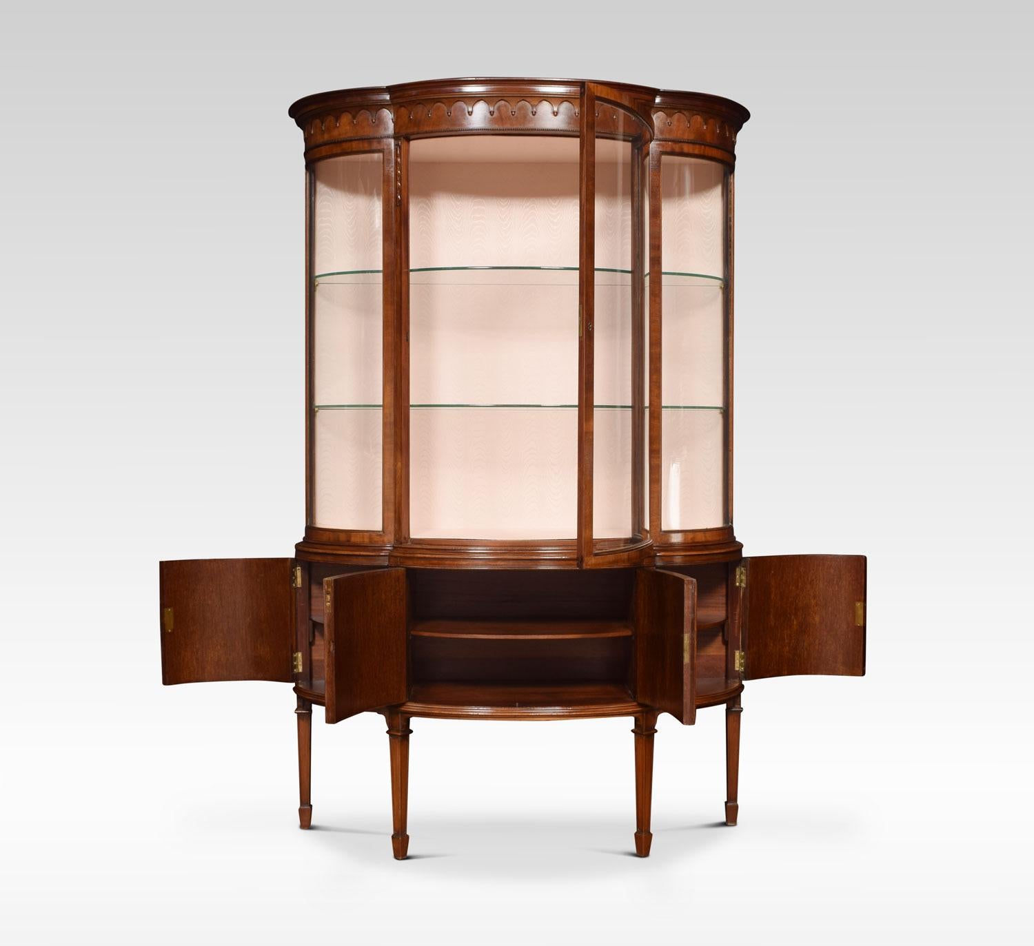 Mahogany display cabinet the moulded cornice above large curved glazed door flanked by two bowed sides. The interior having watermark silk back and two glass shelves. The base section having four flame mahogany paneled doors all raised up on