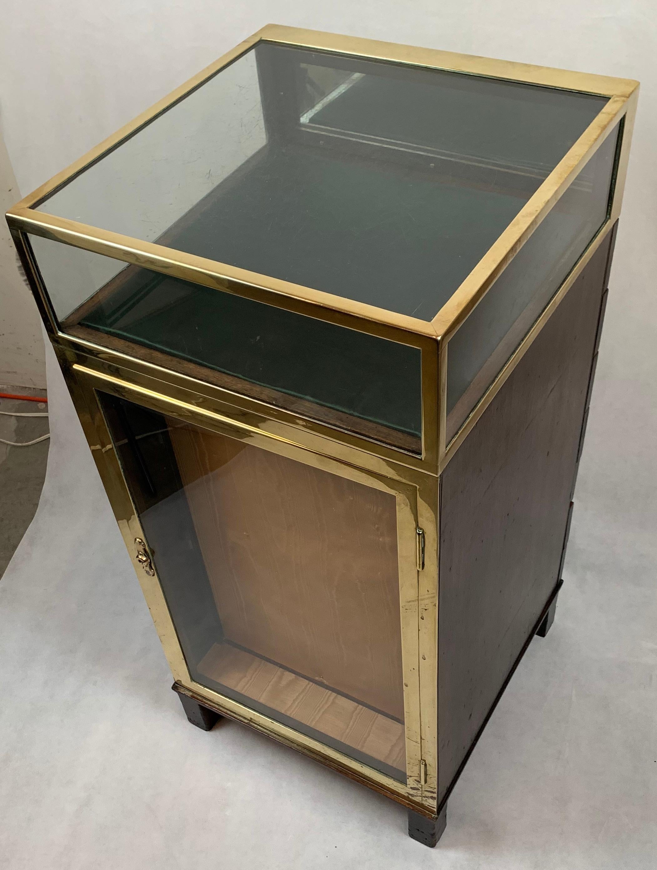 This unusual compact display or collector's cabinet is quite unusual. There is the main display area on the top which can be accessed from the back. The front brass bound glass door opens from the front. There are three glass shelves plus the bottom